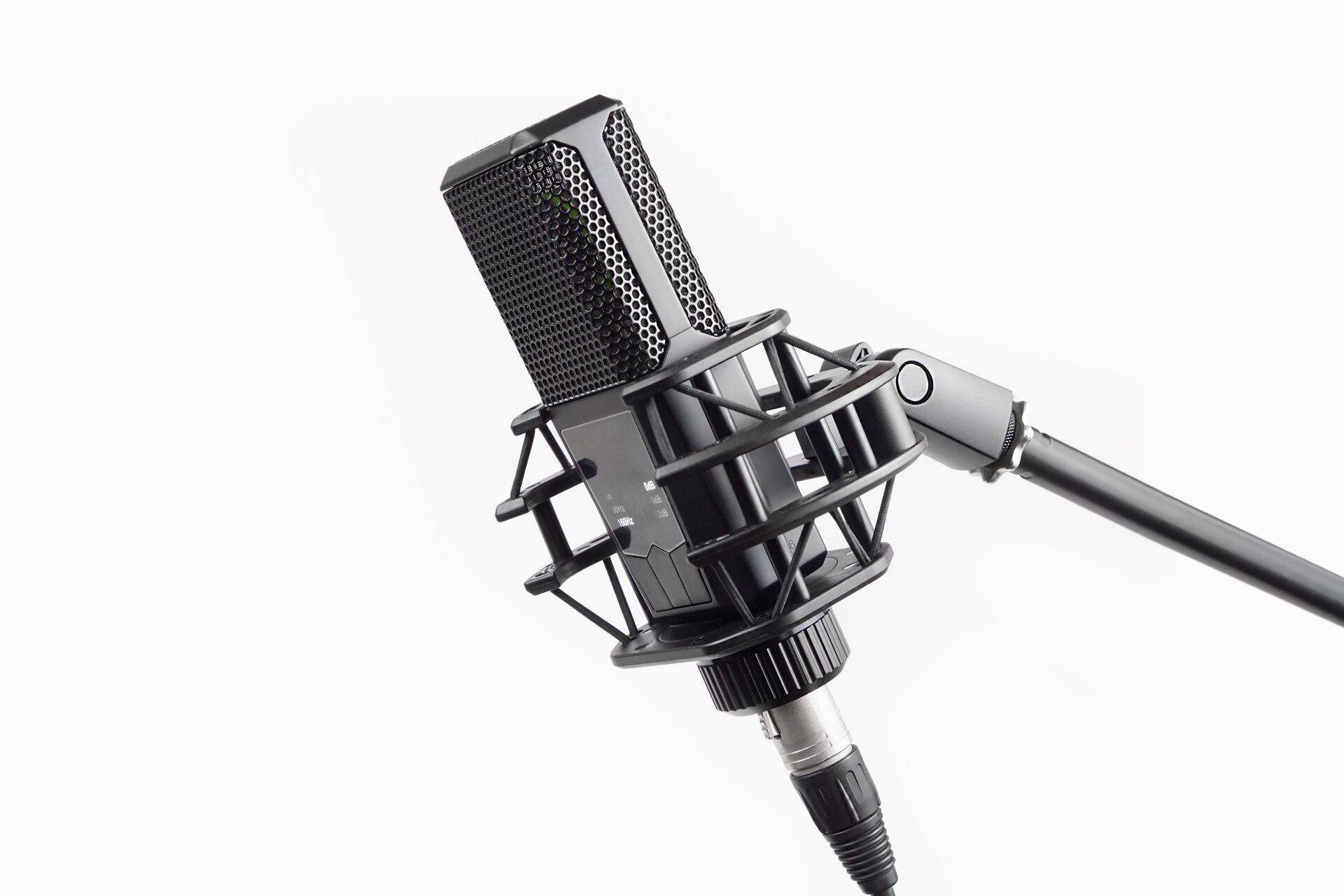 Ilustracja przedstawia mikrofon wstęgowy. Mikrofon jest w kolorze czarnym oraz znajduje się na stojaku. Tło ilustracji jest białe.