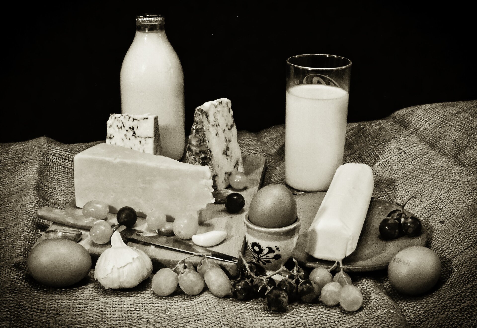Zdjęcie przedstawia różne produkty nabiałowe ustawione na lnianym materiale. To miedzy innymi: mleko, jaja, sery. 