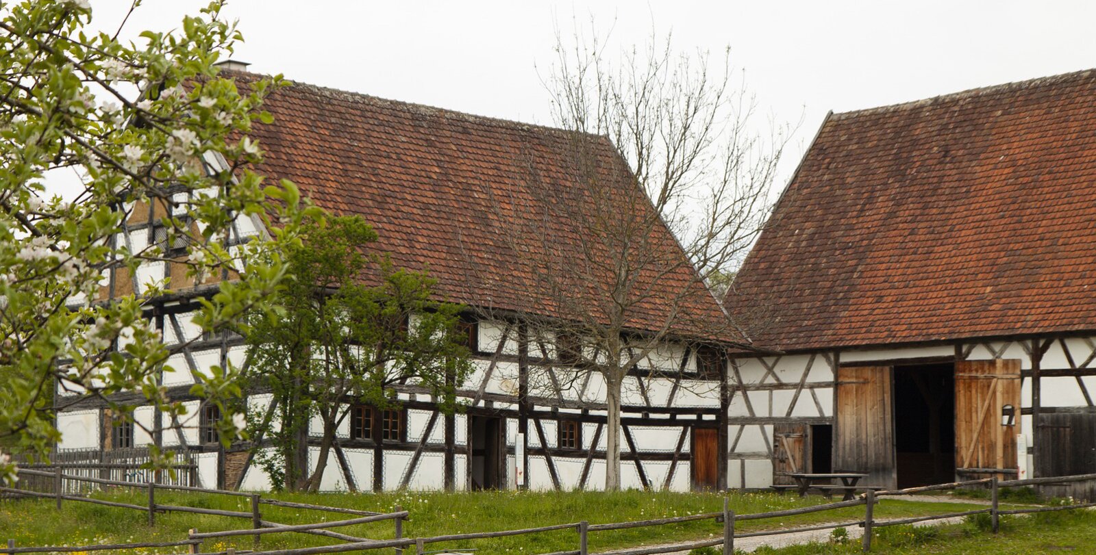 Zdjęcie przedstawia domek na wsi, biała elewacja przepleciona jest widocznymi drewnianymi belkami.