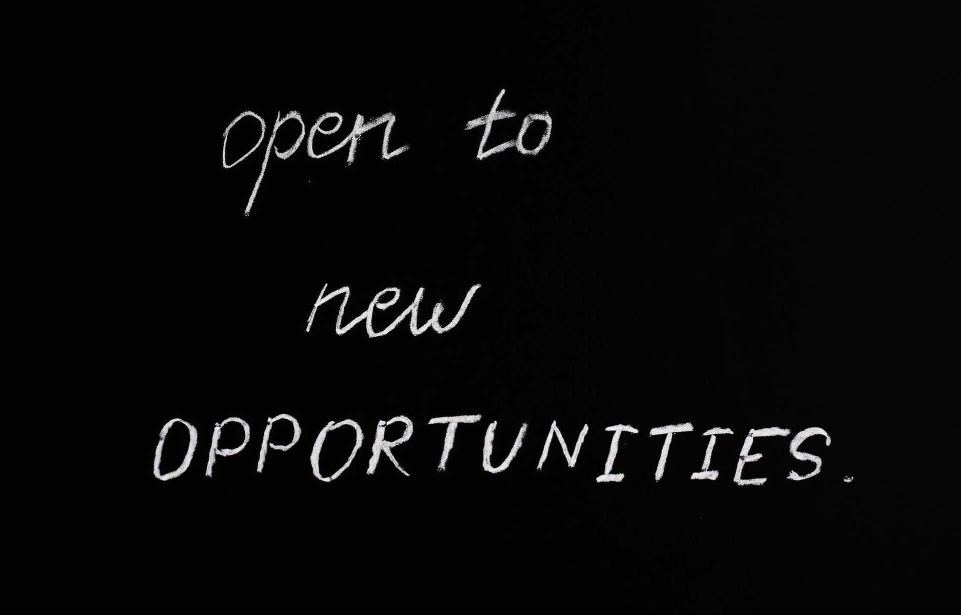 Ilustracja przedstawia czarne tło, na którym widoczny jest napis z białych liter w języku angielskim: open to new opportunities.
