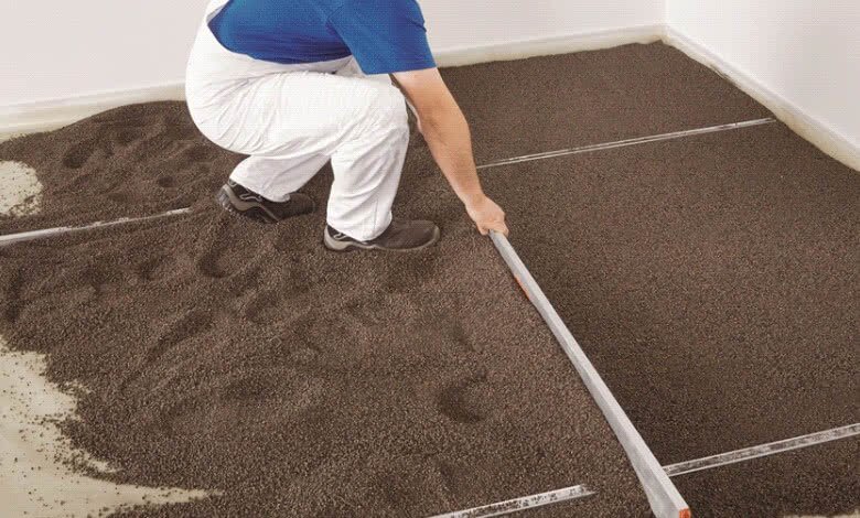 Zdjęcie przedstawia podsypkę z keramzytu pod układanie płyt suchego jastrychu. Widać robotnika, który stoi na bardzo drobnej, ciemnej podsypce.