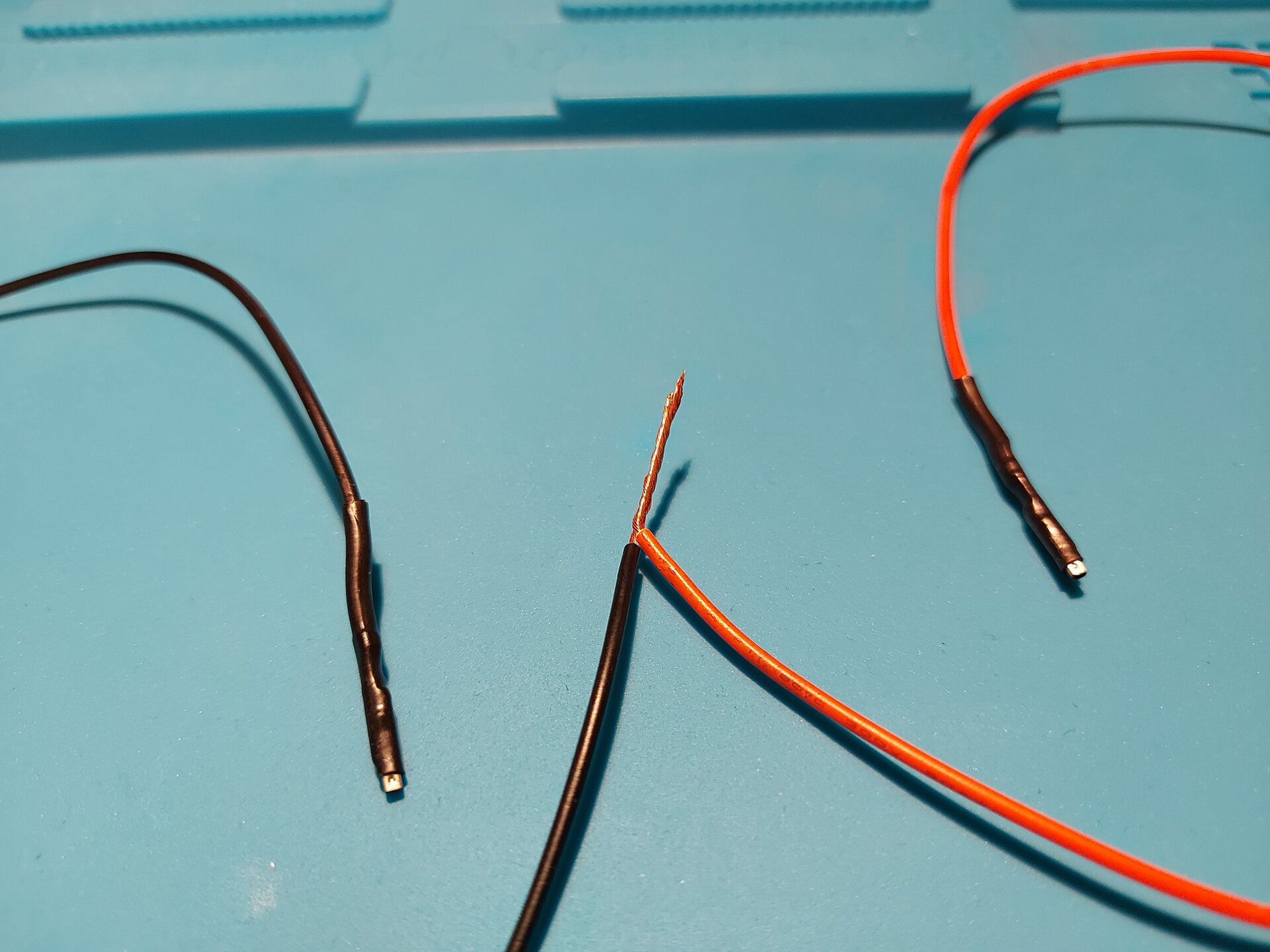 Zdjęcie przedstawia 2 przewody z usuniętą izolacją tym samym odsłaniając miedziane wnętrze, które skręcono ze sobą ustawiając miedziane zakończenia w tym samym kierunku.