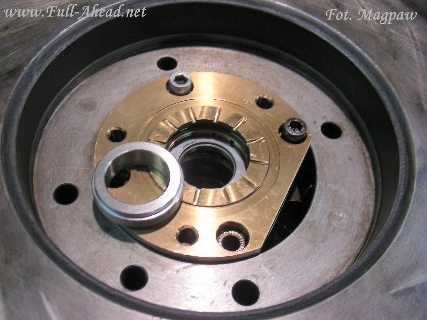 Dziewiąte zdjęcie przedstawia pierścień dystansowy leżący na części turbosprężarki od strony sprężarki.