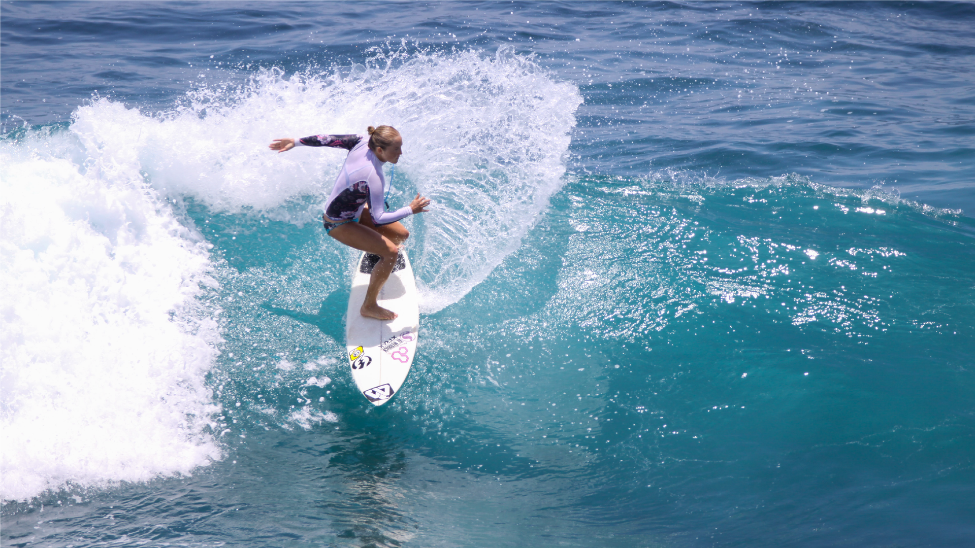 Zdjęcie przedstawia kobietę płynącą na desce surfingowej.
