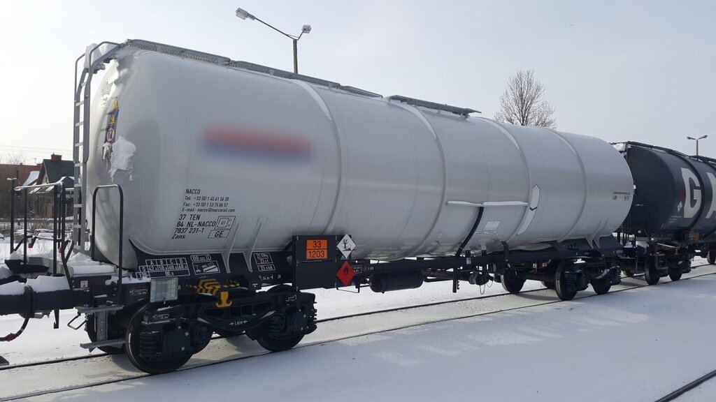 Ilustracja przedstawia wagon cysternę, na której znajdują się nalepki i tablice informacyjne. Nalepki i tablice znajdują się w tylnej części wagonu.