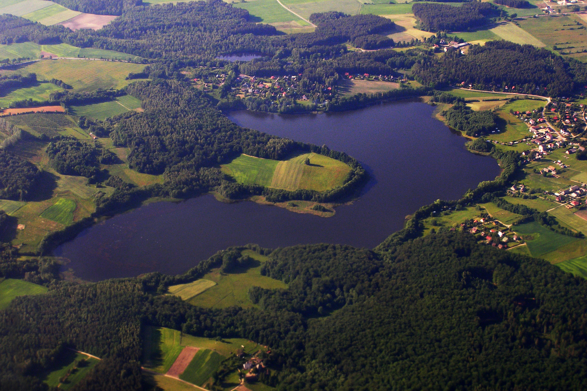 Fotografia wykonana z lotu ptaka ukazuje jeziora Pojezierza Pomorskiego. Wokół jeziora liczne lasy oraz łąki i pola.