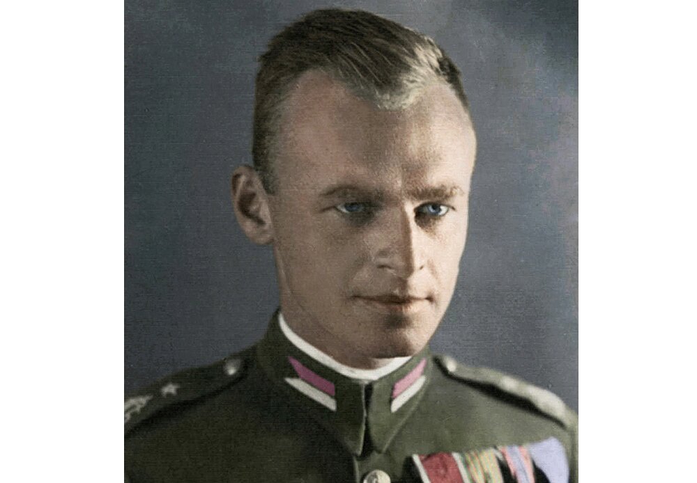 Fotografia barwna przedstawiająca Witolda Pileckiego. Ma jasne, zaczesane gładko włosy. Patrzy poza kadr. Ubrany jest w zielony mundur, na którym znajduje się wiele odznaczeń. Ma jasne, bystre oczy.