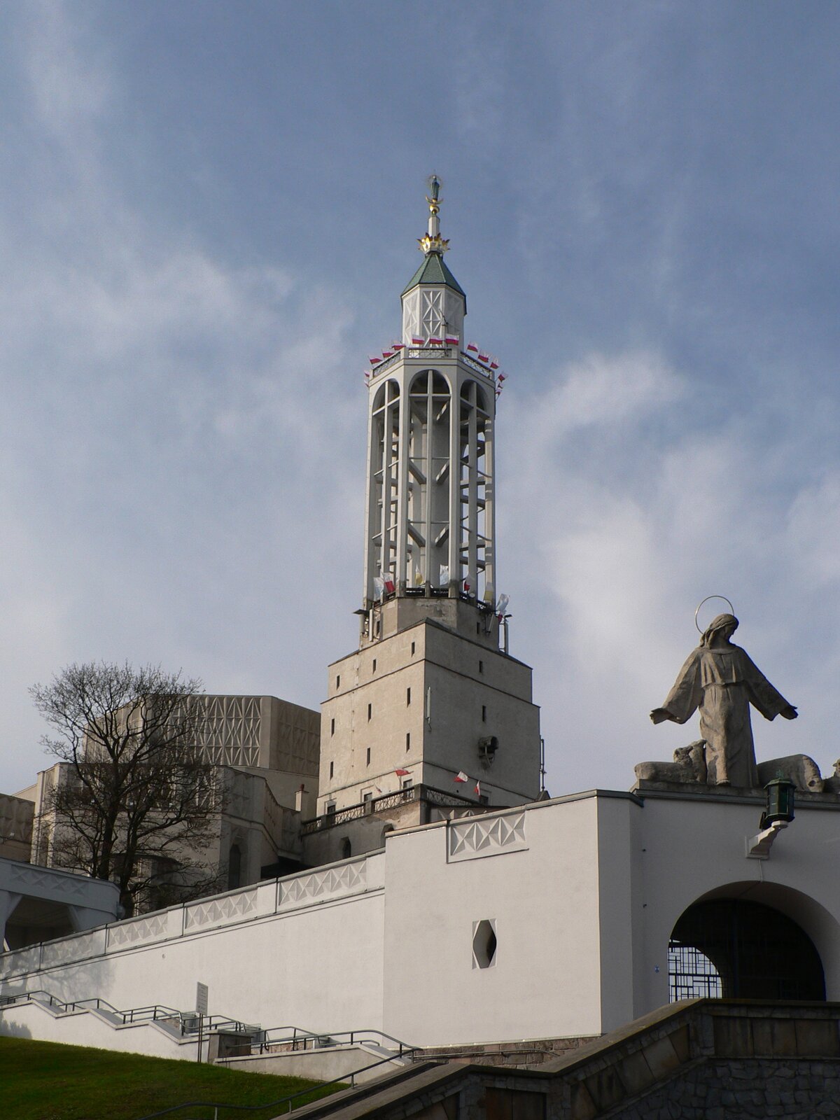 Ilustracja przedstawia Bazylikę św. Rocha w Białymstoku. Kościół zbudowany został w stylu modernistyczno-ekspresjonistycznym na planie ośmioboku i składa się z trzech stopniowo narastających brył. Pierwsza bryła tworzy zasadniczy element świątyni, na szczycie budynku znajduje się ażurowa wieża z tarasem widokowym. Nad łukowatym wejściem znajduje się się rzeźba Chrystusa.