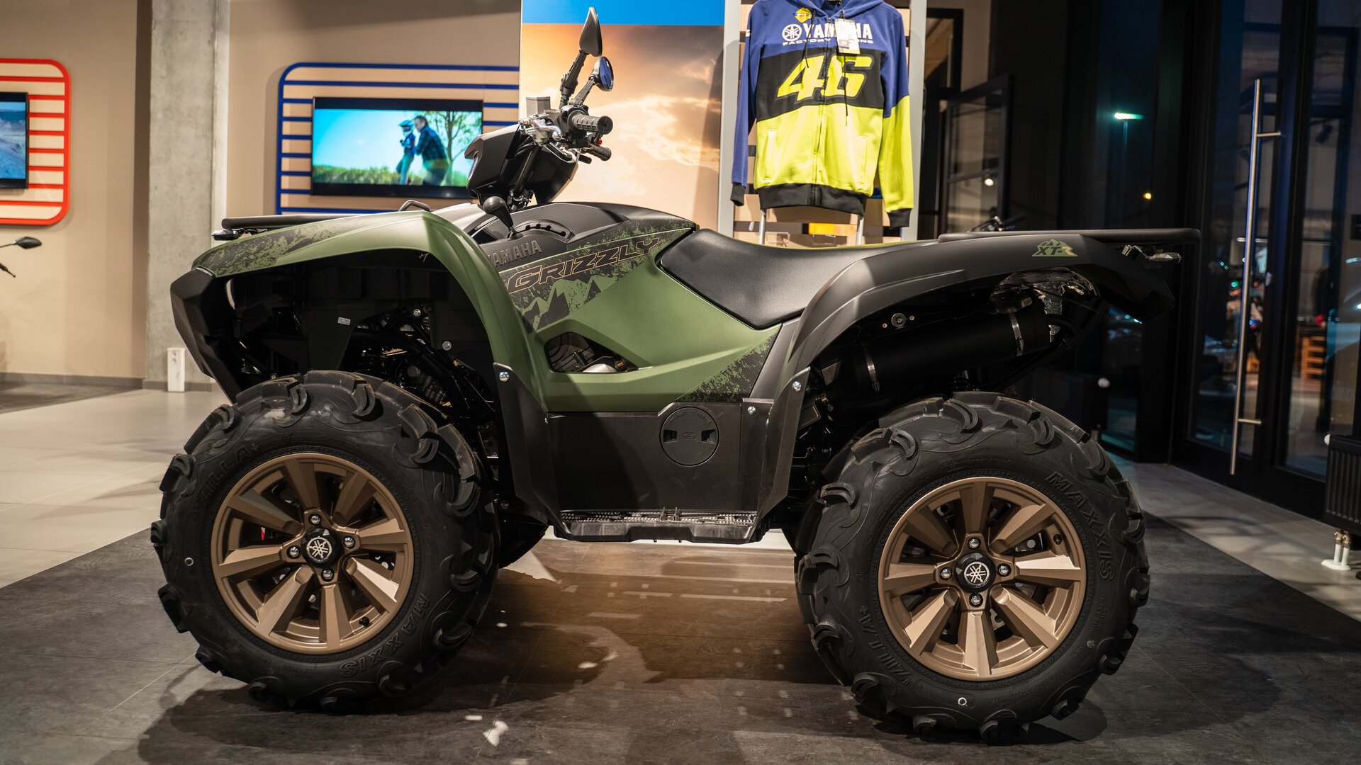 Zdjęcie przedstawia pojazd czterokołowy. Pojazd ma grube opony. Nie posiada dachu, drzwi, szyb. Ma kierownicę jak w motocyklu. 