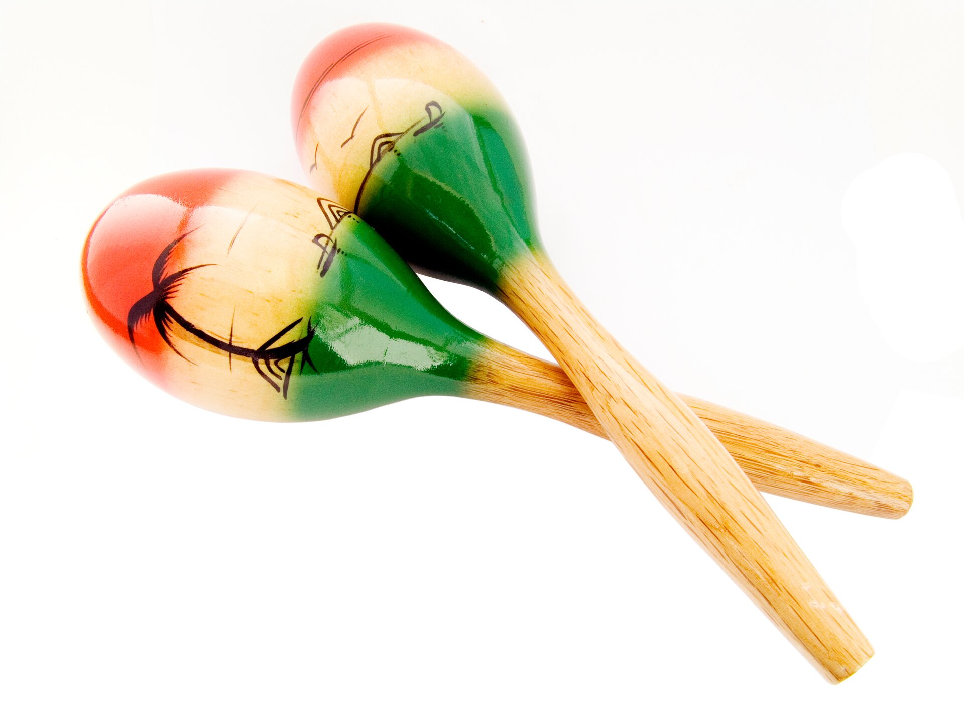 Zdjęcie przedstawia marakasy, czyli dwa identyczne drewniane instrumenty w obłym kształcie, z podłużną rączką. Obłe elementy pomalowane są czerwoną i zieloną farbą z detalami w kształcie palmy.