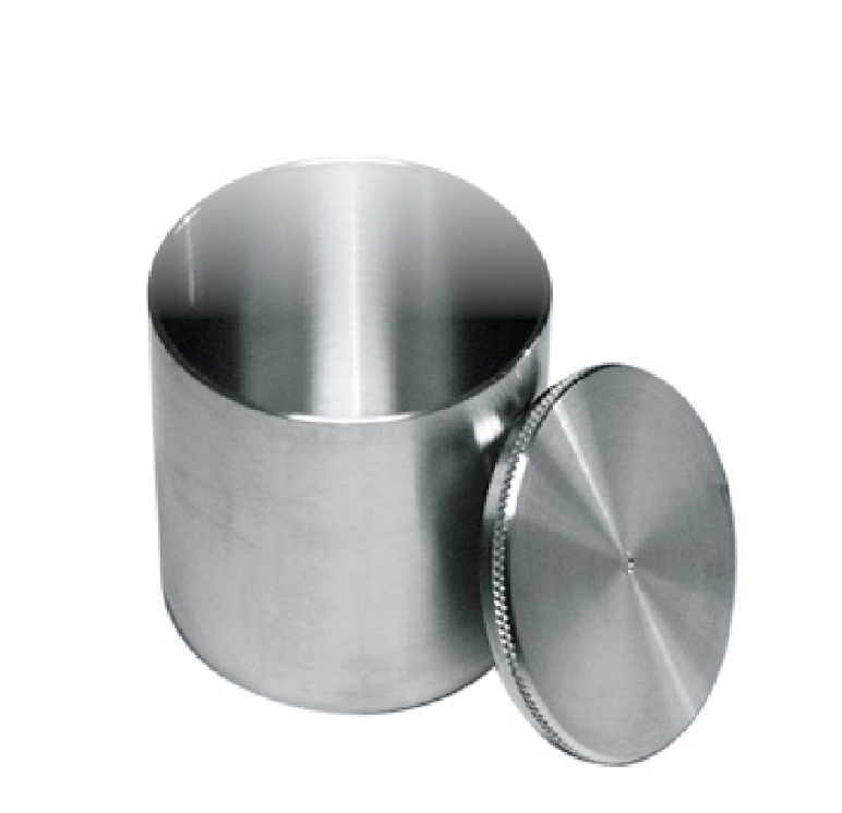 Ilustracja przedstawia piknometr. Zbudowany jest on z walcowatego, stalowego pojemnika i okrągłej pokrywy, na środku której znajduje się niewielki otwór.