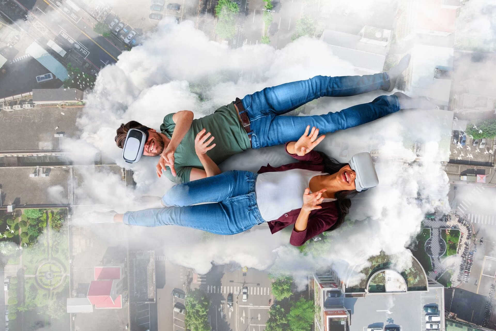 Grafika przedstawia leżących na chmurze mężczyznę i kobietę w goglach VR. W dole widać ulice i budynki. 