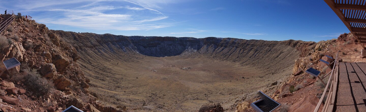 Fotografia prezentuje panoramę szerokiego i głębokiego wklęśnięcia w Ziemi nazywanego kraterem.