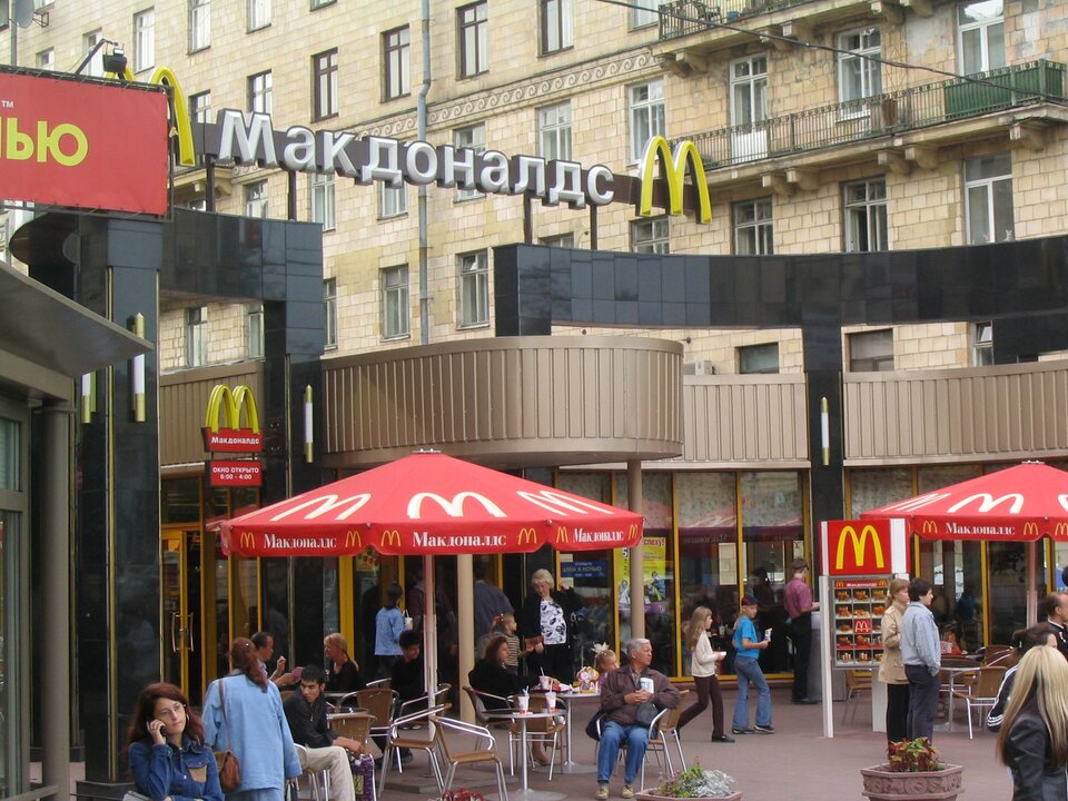 Zdjęcie przedstawia restaurację sieci McDonald's z charakterystycznym logo, przedstawiającym duże M. Na fotografii nazwa sieci napisana na budynku rosyjskimi literami. 