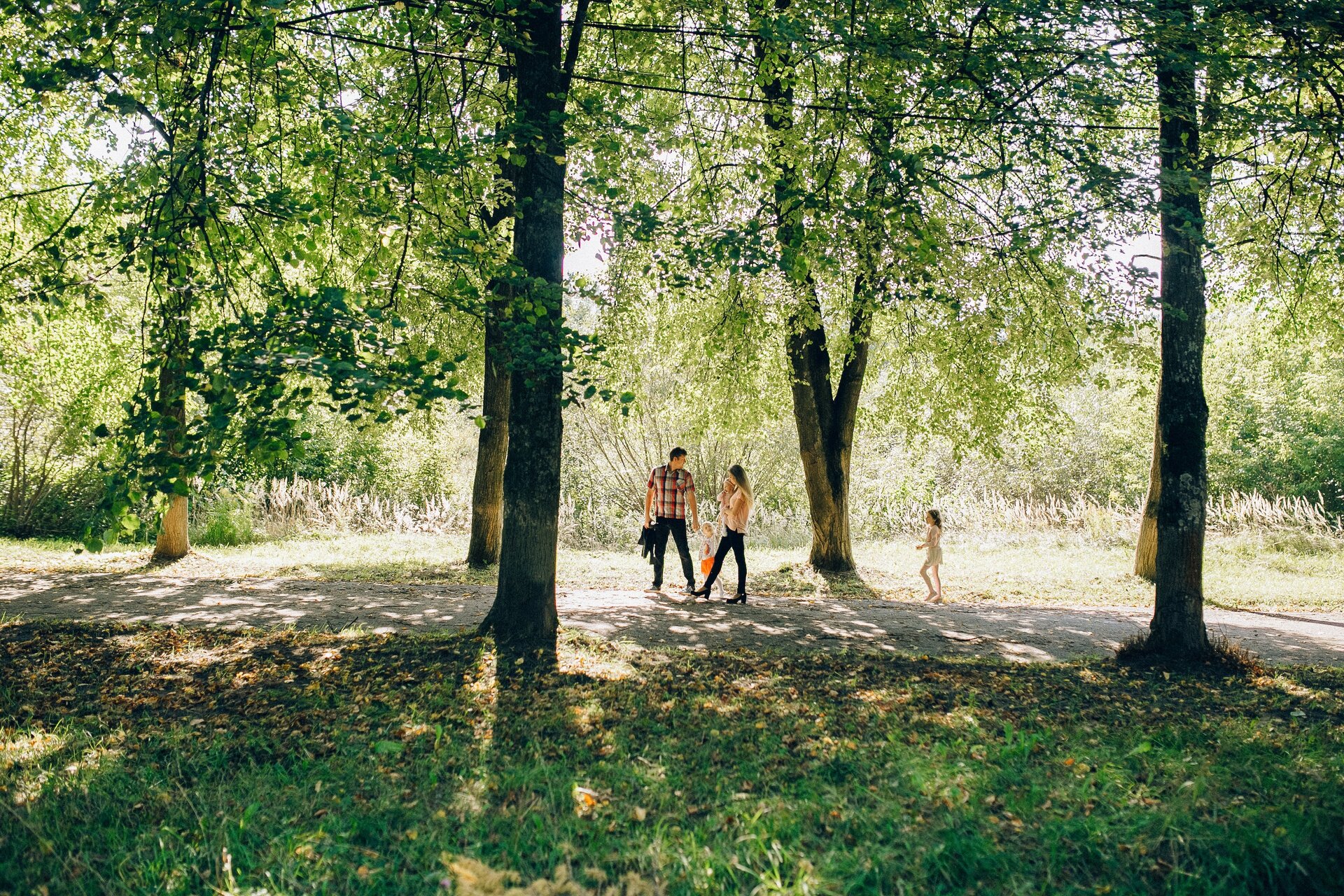 Ilustracja przedstawia kobietę, mężczyznę i dziecko podczas spaceru w parku.
