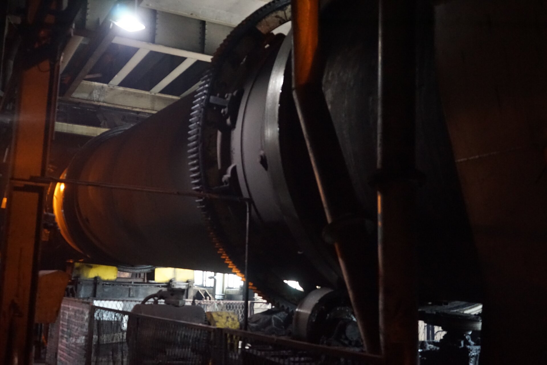 Zdjęcie przedstawia bęben suszarki. Suszarka bębnowa składa się z obracającej się walcowatej komory, czyli bębna. Jest on zorientowany poziomo i zamontowany na pewnej wysokości. Poniżej zdjęcia znajduje się przycisk multimedialny z nagraniem audio. Treść nagrania jest zgodna z tytułem zdjęcia.