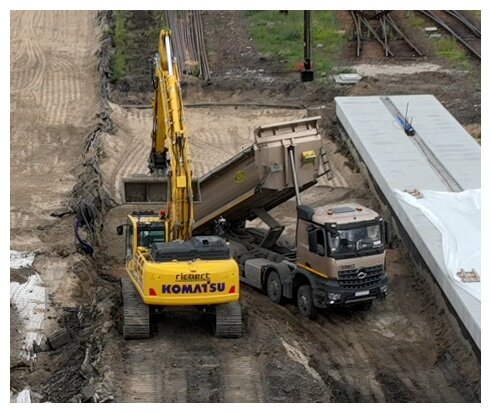 Ilustracja przedstawia koparkę gąsiennicową w trakcie pracy na budowie. Maszyna na zdjęciu profiluje warstwę podtorza przy użyciu gruntu rodzimego, który został przywieziony przez wywrotkę.