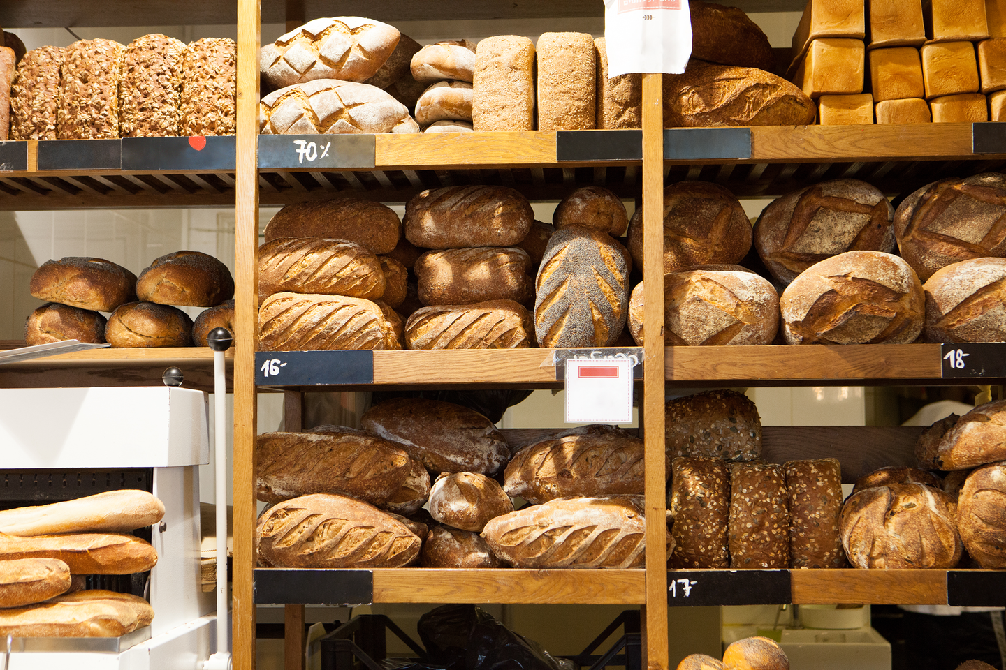 Fragment piekarni z widocznym na półkach pieczywem. Pieczywa jest dużo. jest różnorodne - chleby, bagietki.