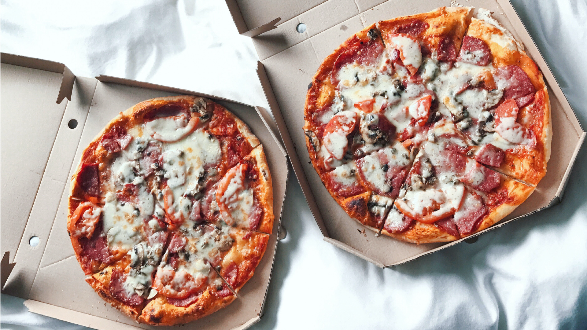 Zdjęcie przedstawia dwie pizze w pudełkach.