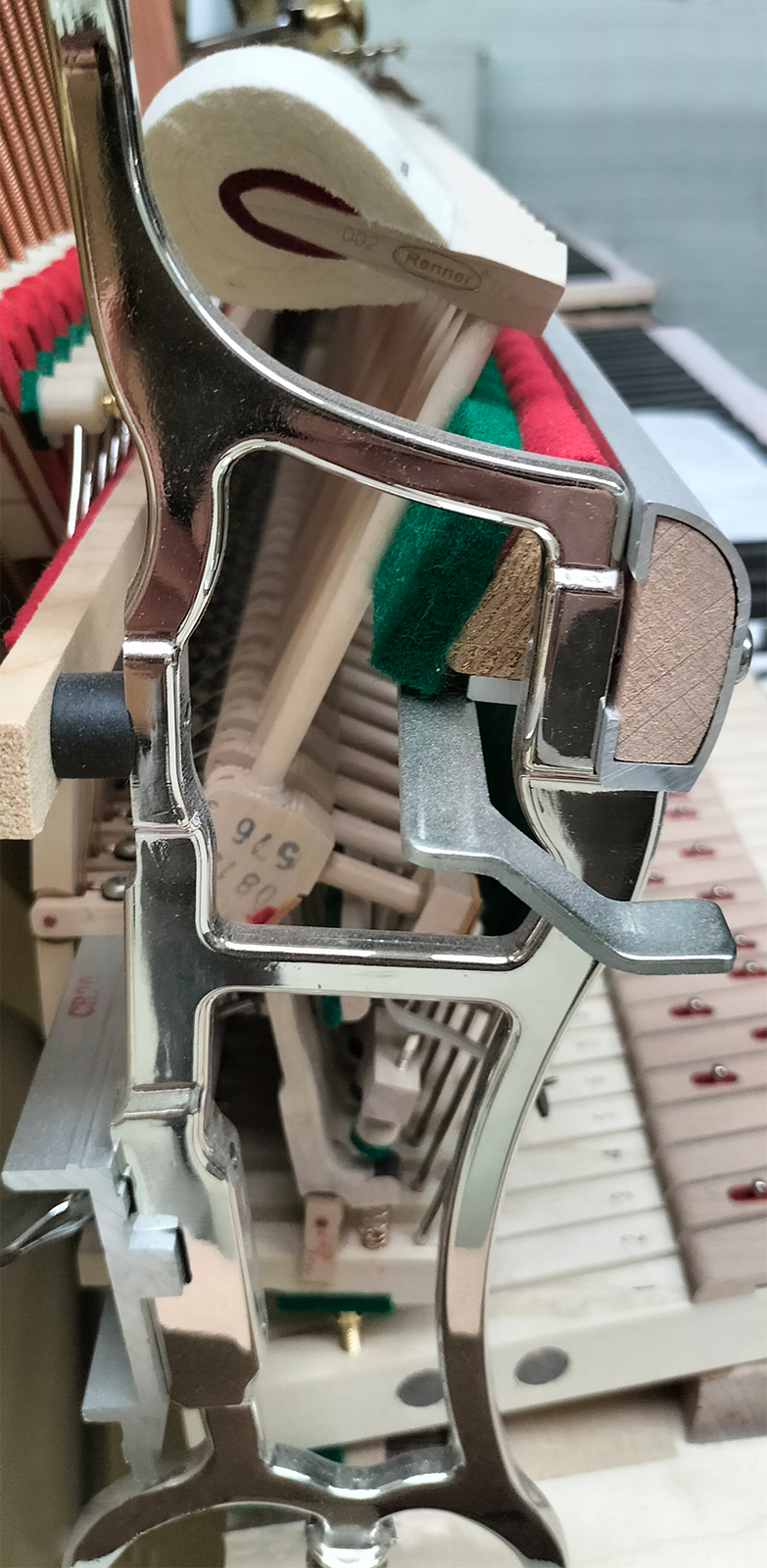 Zdjęcie przedstawia mechanizm pianinowy wykonany z różnych elementów metalowych.