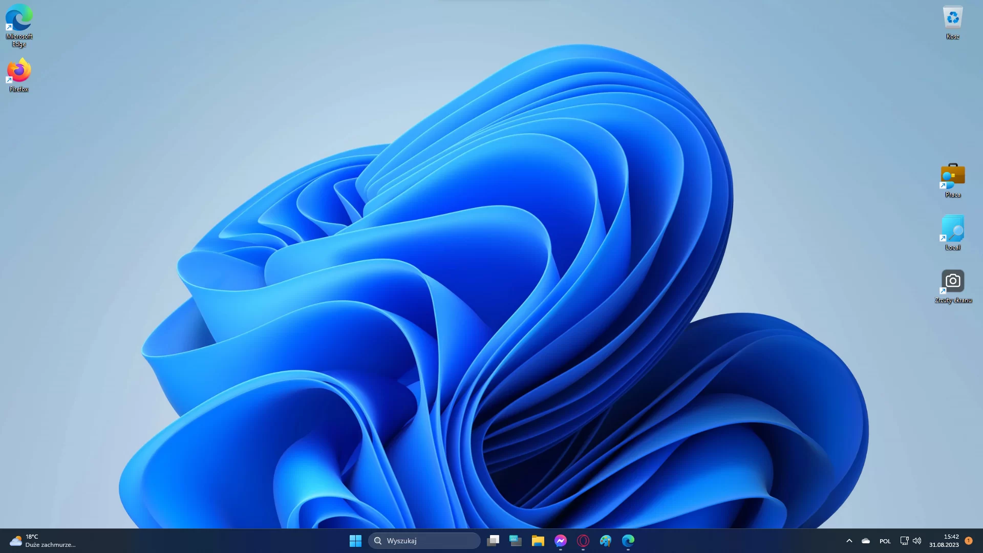 Na zdjęciu przedstawiono zrzut pulpitu dla systemu Windows 11. Na zdjęciu widać jasnoniebieską tapetę.  Na tapecie w środkowej części widoczna jest abstrakcyjna niebieska figura. Na tapecie, w lewym górnym rogu znajdują się ikony podpisane jako: kosz, Local, Praca, Zrzuty ekranu, Microsoft Edge, Google Chrome oraz CCleaner, zdjęcia.Poniżej tapety znajduje się pasek narzędzi. Po lewej stronie paska znajduje się widżet z pogodą. Po środku logo Windows oraz skróty do odpalania aplikacji. Po prawej stronie widoczne są ustawienia oraz godzina z datą.