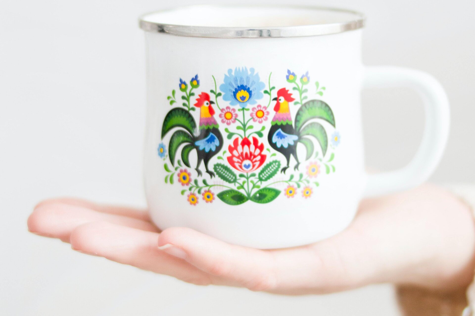 Ilustracja przedstawia kubek ozdobiony wzorem ludowym. 