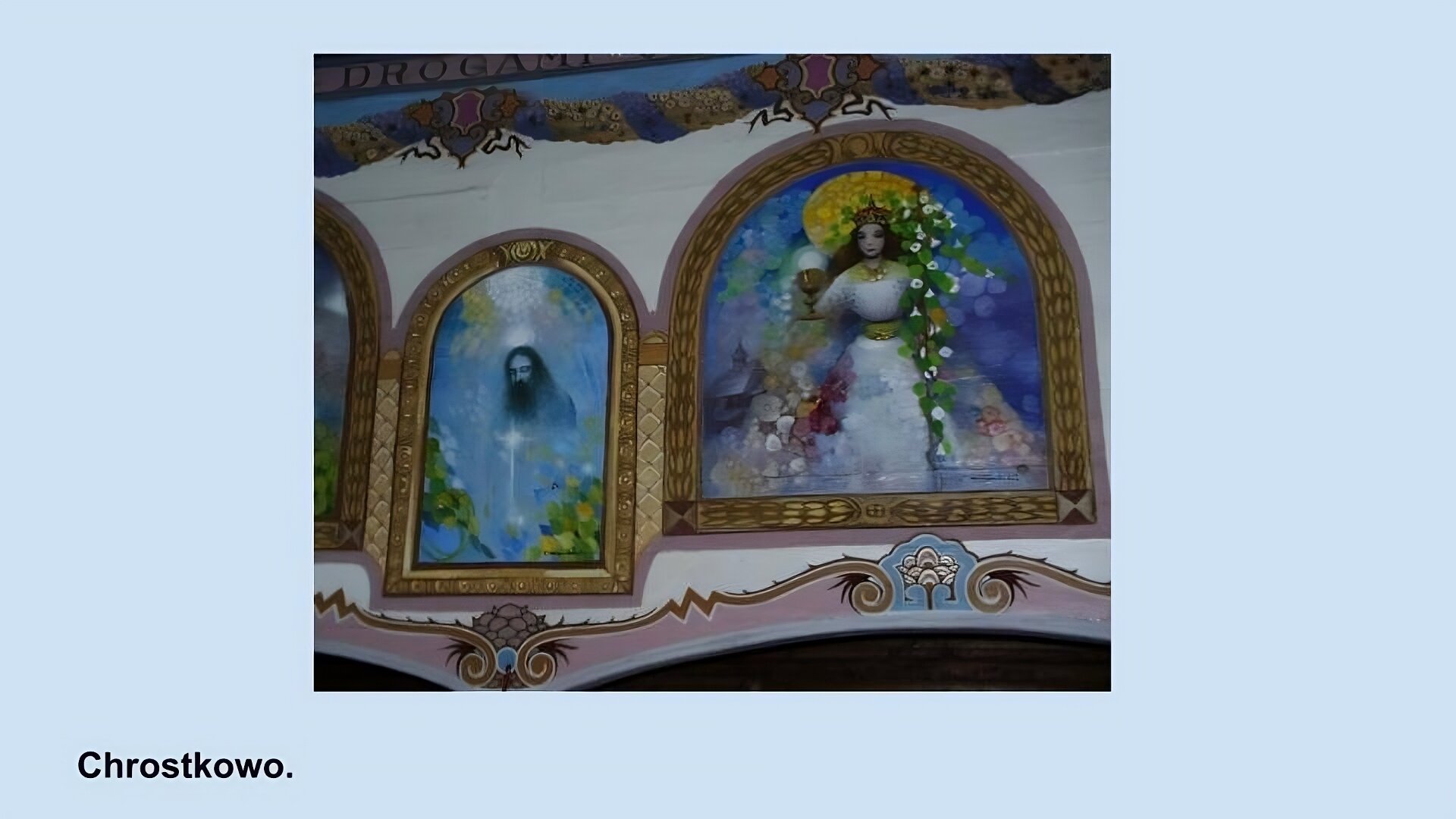 Zdjęcie przedstawia malunki na ścianie kościoła w Chrostkowie. W złotych ramkach z łukami. P lewej stronie mniejszy obrazek przedstawiający brodatego mężczyznę na niebieskim tle z poświatą na piersi i kwiatowymi elementami w dolnych rogach. Po prawej większe malowidło przedstawiające kobietę w białej sukni, koronie trzymającej w jednej ręce kielich a w drugiej krzyż porośnięty białymi kwiatami i liścmi. Z tyłu niebieskie tło i kościół.  