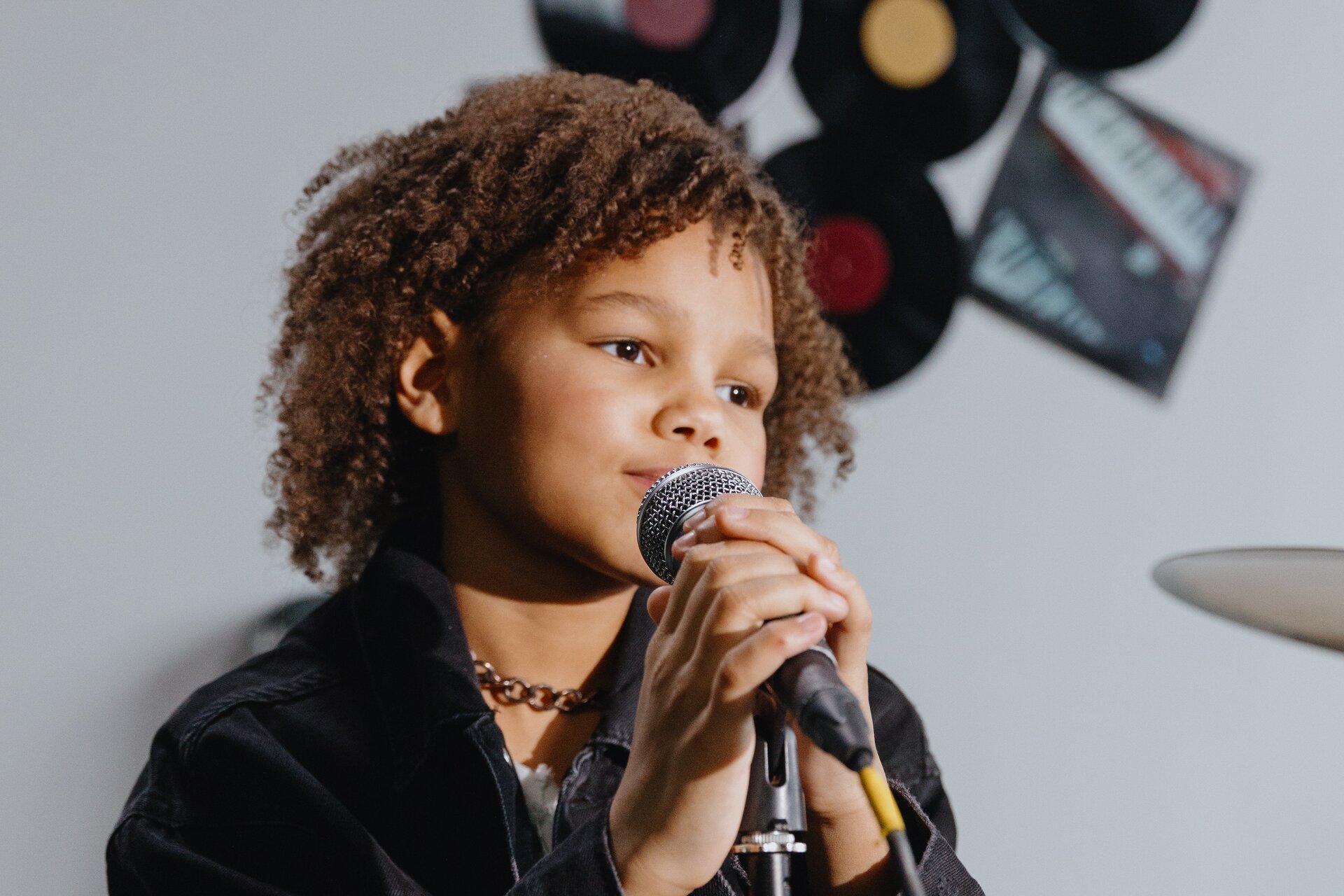 Ilustracja przedstawia dziewczynkę z mikrofonem.