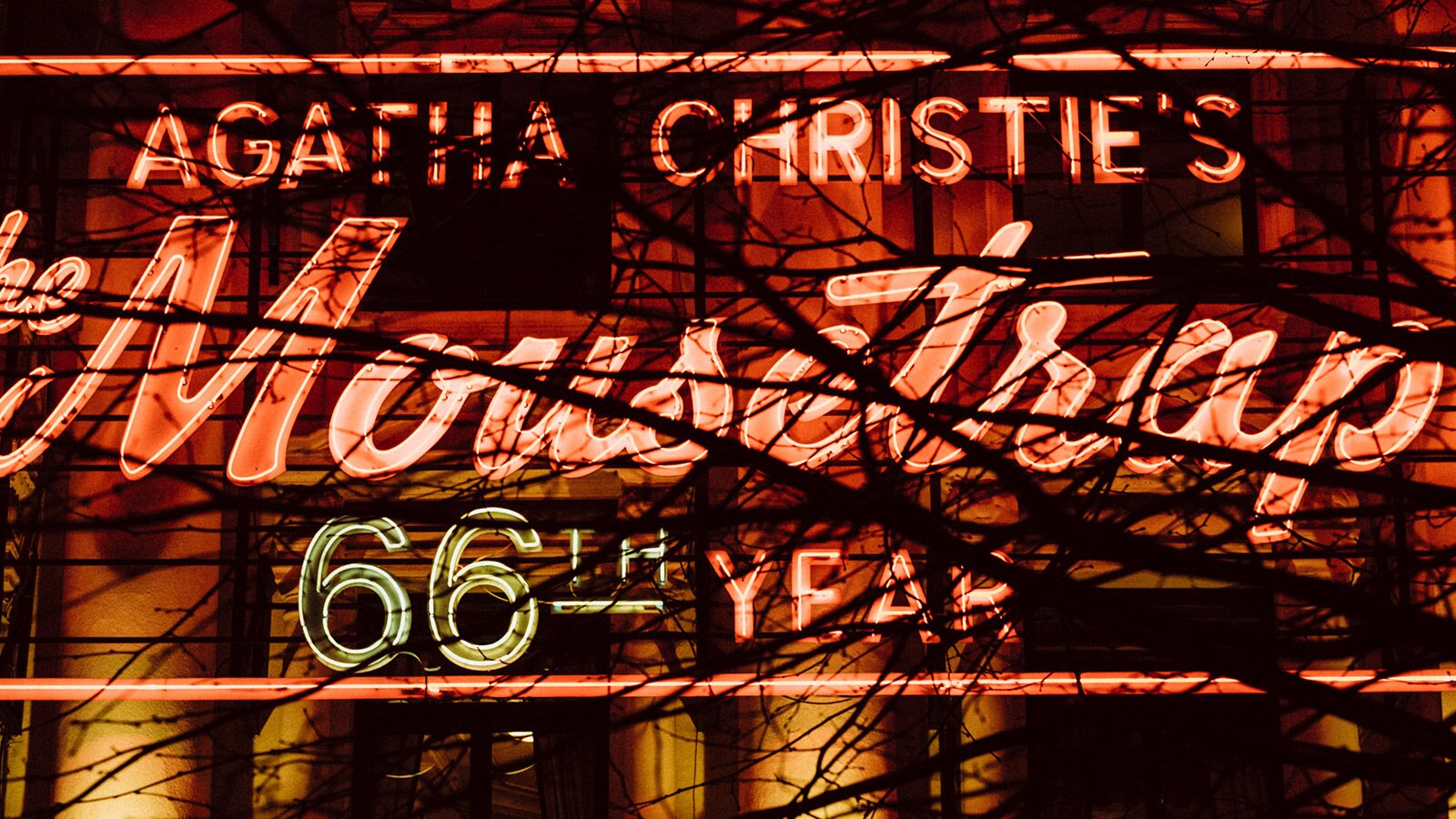 Zdjęcie przedstawia świecący się neonowy napis reklamujący przedstawienie. Widoczny jest napis: AGATHA CHRISTIE’S Mousetrap 66TH YEAR.