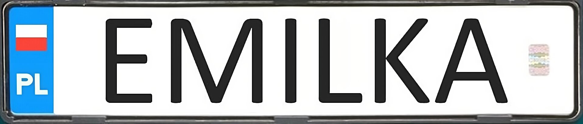 Zdjęcie przedstawia tablicę rejestracyjną indywidualną. Jest to prostokąt z białym tłem. 
Od lewej niewielki niebieski fragment w postaci prostokąta, na którym jest umieszczony symbol kraju (PL). Powyżej biało‑czerwony kwadrat symbolizujący polską flagę. Na środku tablicy na białym tle czarnymi literkami napis Emilka. Po prawej stronie na białym tle widoczna naklejka legalizacyjna.
