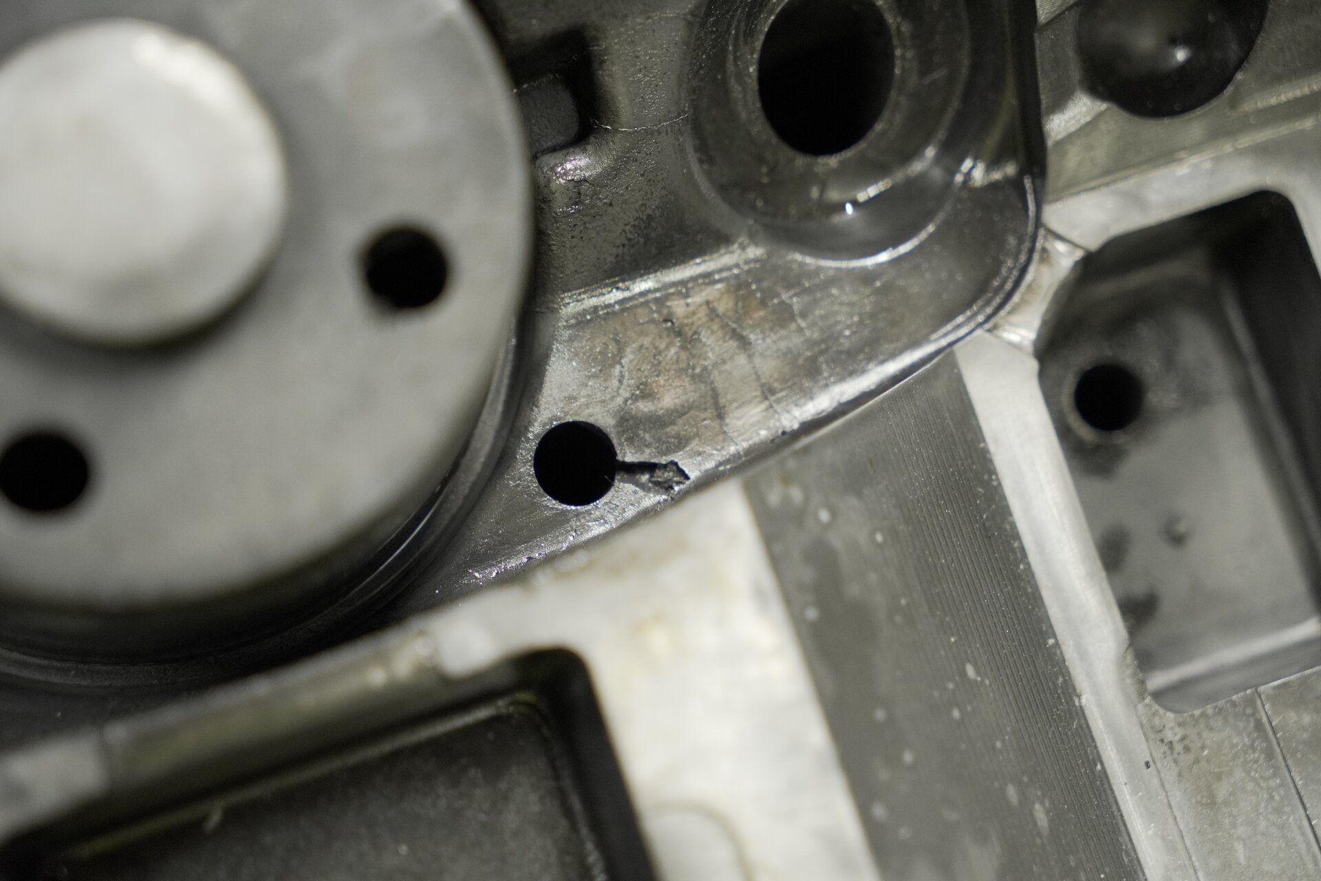 Ilustracja przedstawia uszkodzoną formę metalową. Widoczna jest wnęka formy oraz otwór, z którego wykruszony jest kawałek powierzchni.