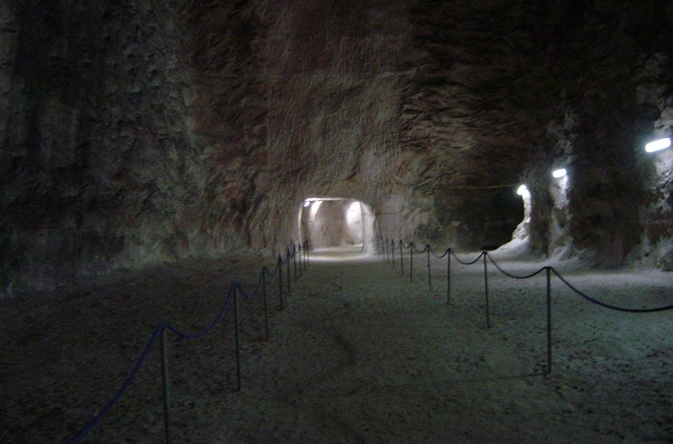 Zdjęcie przedstawia korytarz największej czynnej kopalni soli kamiennej w Polsce, która znajduje się w Kłodawie. Jest to fragment trasy turystycznej, szerokie i bardzo wysokie pomieszczenie z wytyczoną ścieżką dla zwiedzających, w całości wydrążone w pokładzie soli.