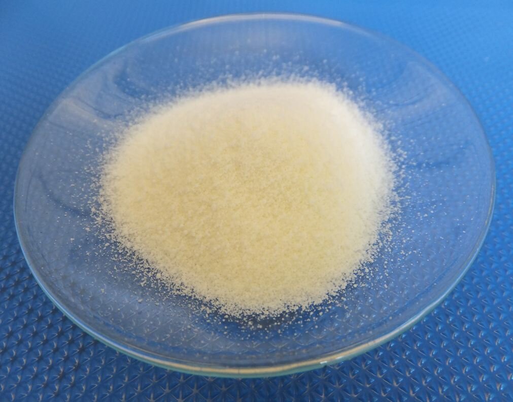 Na zdjęciu na szkiełku zegarkowym leży pewna ilość białego proszku. 