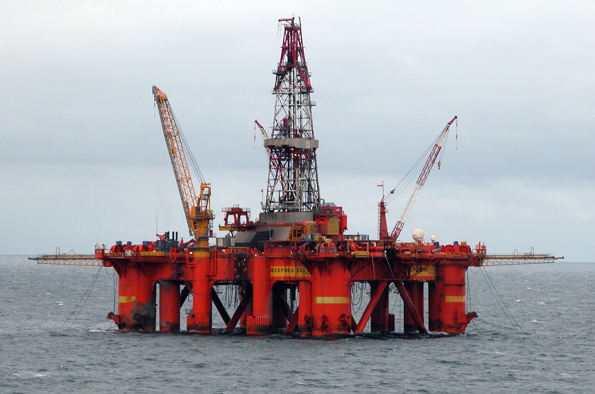 Zdjęcie przedstawia platformę wiertniczą Deepsea Delta firmy Odfjell Drilling na Morzu Północnym. Platforma umieszczona jest na grubych, czerwonych palach wbitych w dno morza. Jest rozległa, w górę w centralnej części wystaje z niej duży stalowy maszt, który otaczają wysokie dźwigi. Dookoła platformy znajduje się woda z falami. 