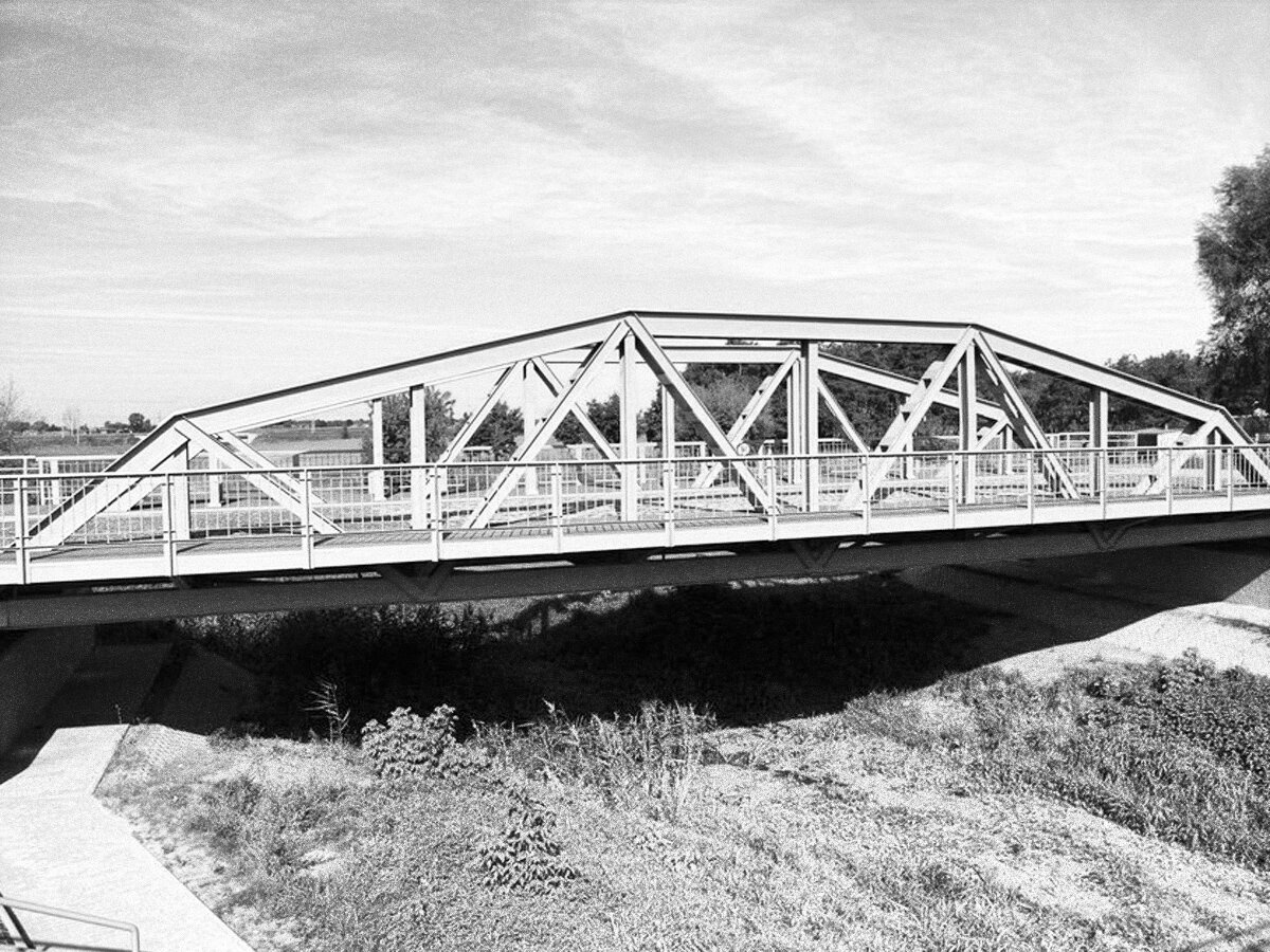 Zdjęcie przedstawia most spawany nad wyschniętą rzeką.