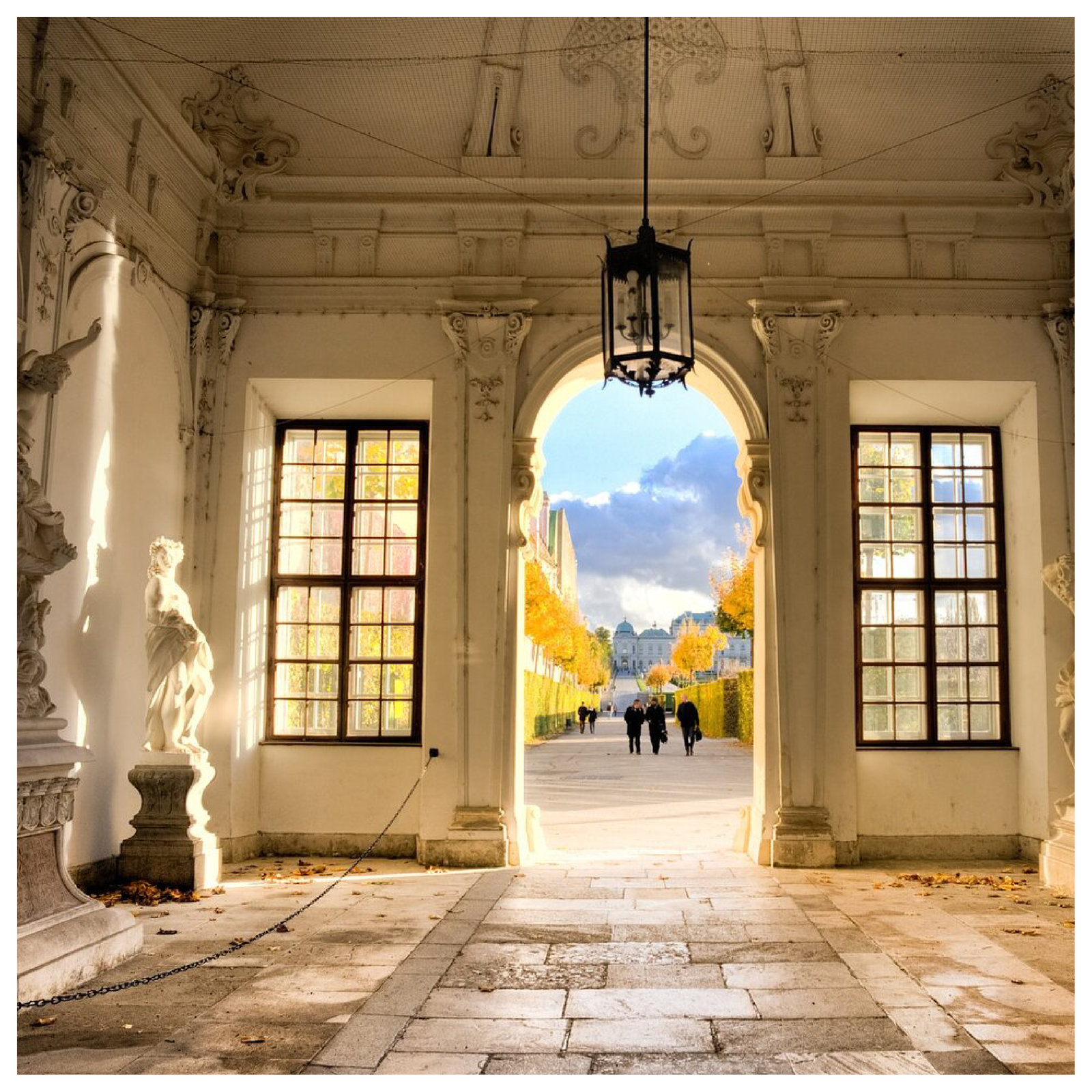 Ilustracja przedstawia wnętrze sali muzealnej z kamienną podłogą i rzeźbami. 