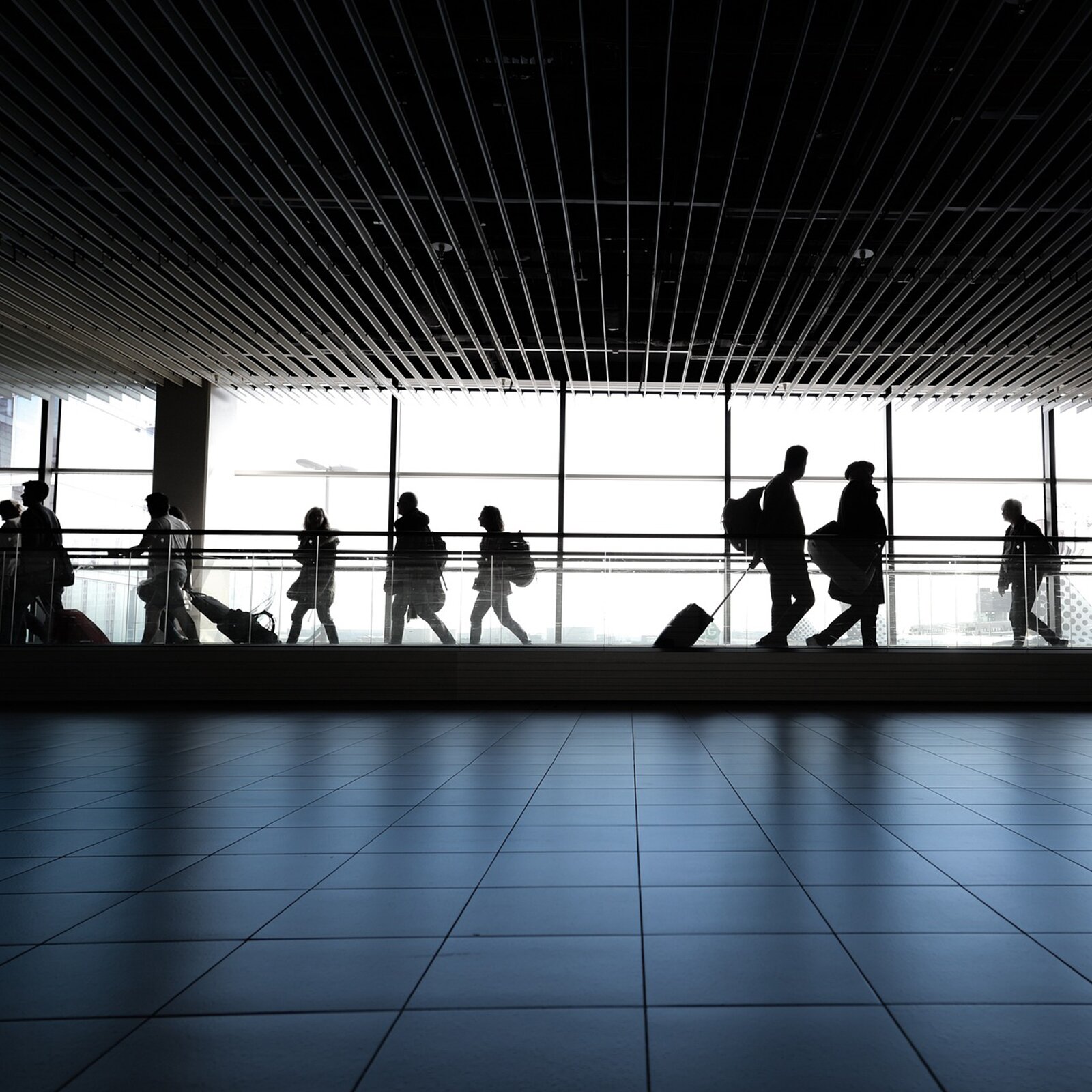 Zdjęcie przedstawia ludzi chodzący w terminalu lotniska.