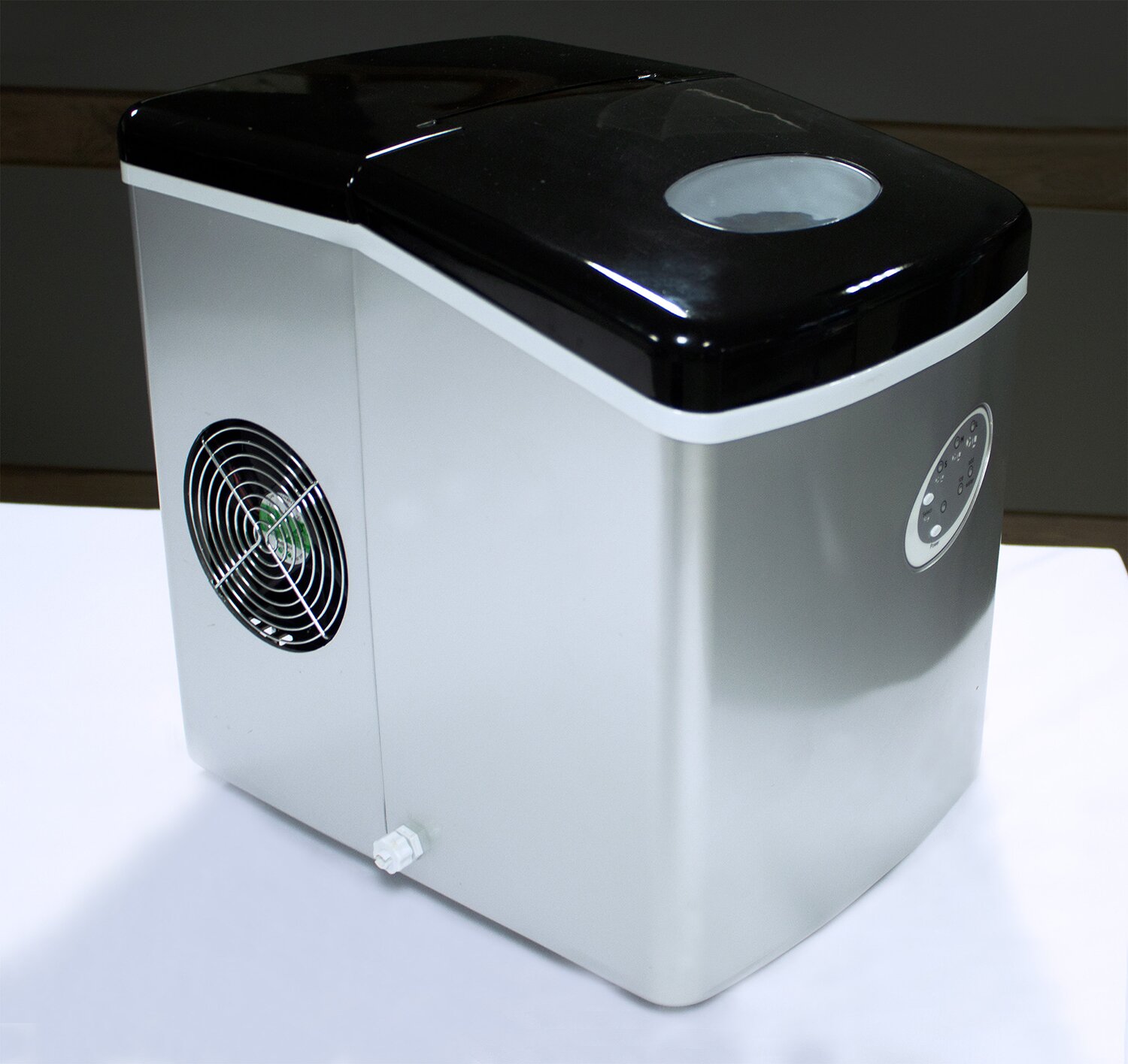 Na zdjęciu znajduje się szara skrzynka z czarnym wieczkiem. Na boku skrzynki umieszczone są przyciski i wywietrzniki.