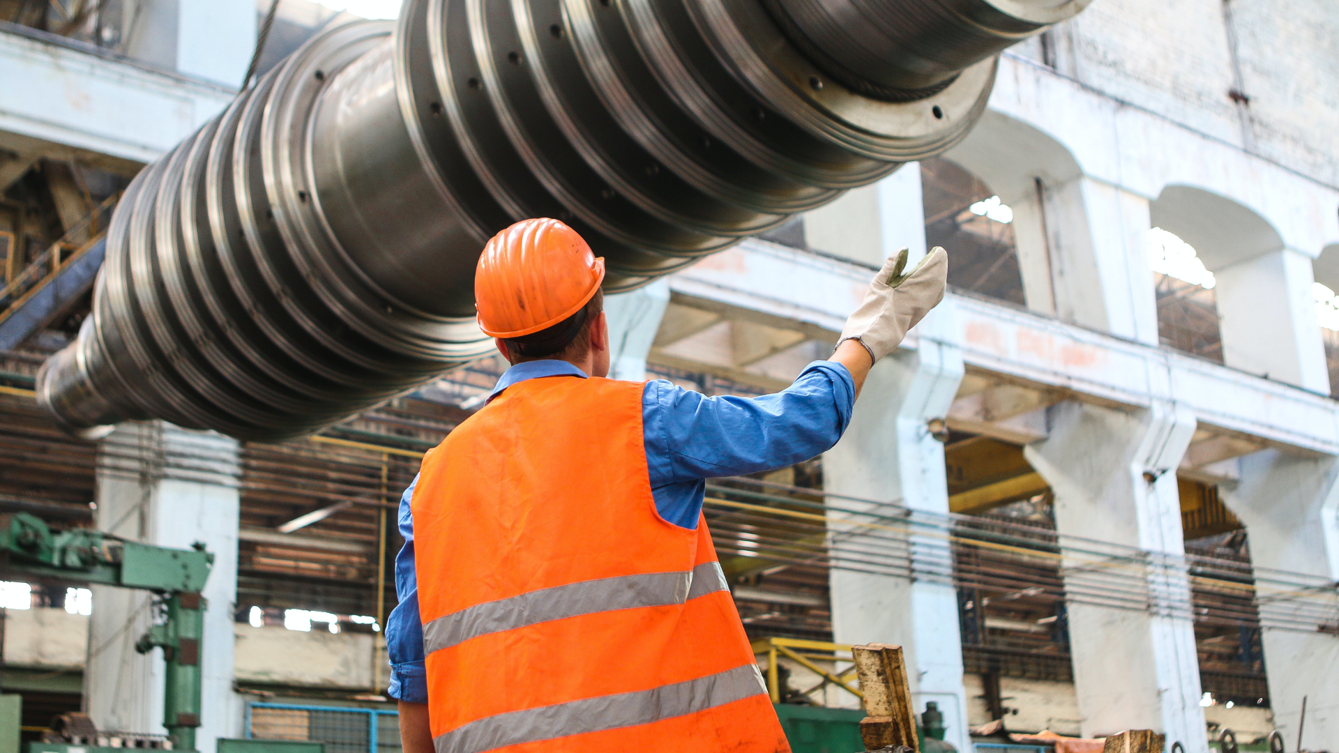 Zdjęcie przedstawia mężczyznę w kasku ochronnym i kamizelce odblaskowej w trakcie prac budowlanych.