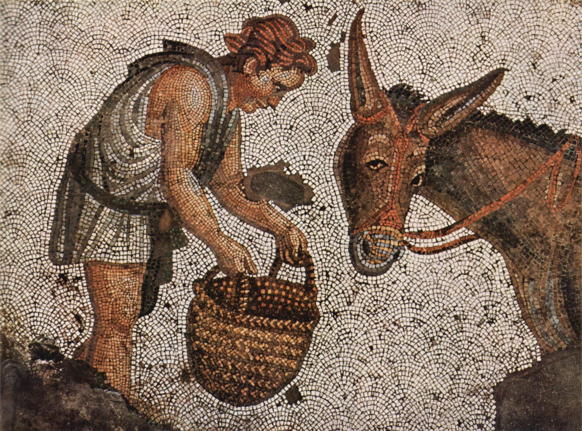 Zdjęcie mozaiki, na której widoczny jest mężczyzna z koszem w rękach. Mężczyzna nachyla się w kierunku osła, próbując go nakarmić.