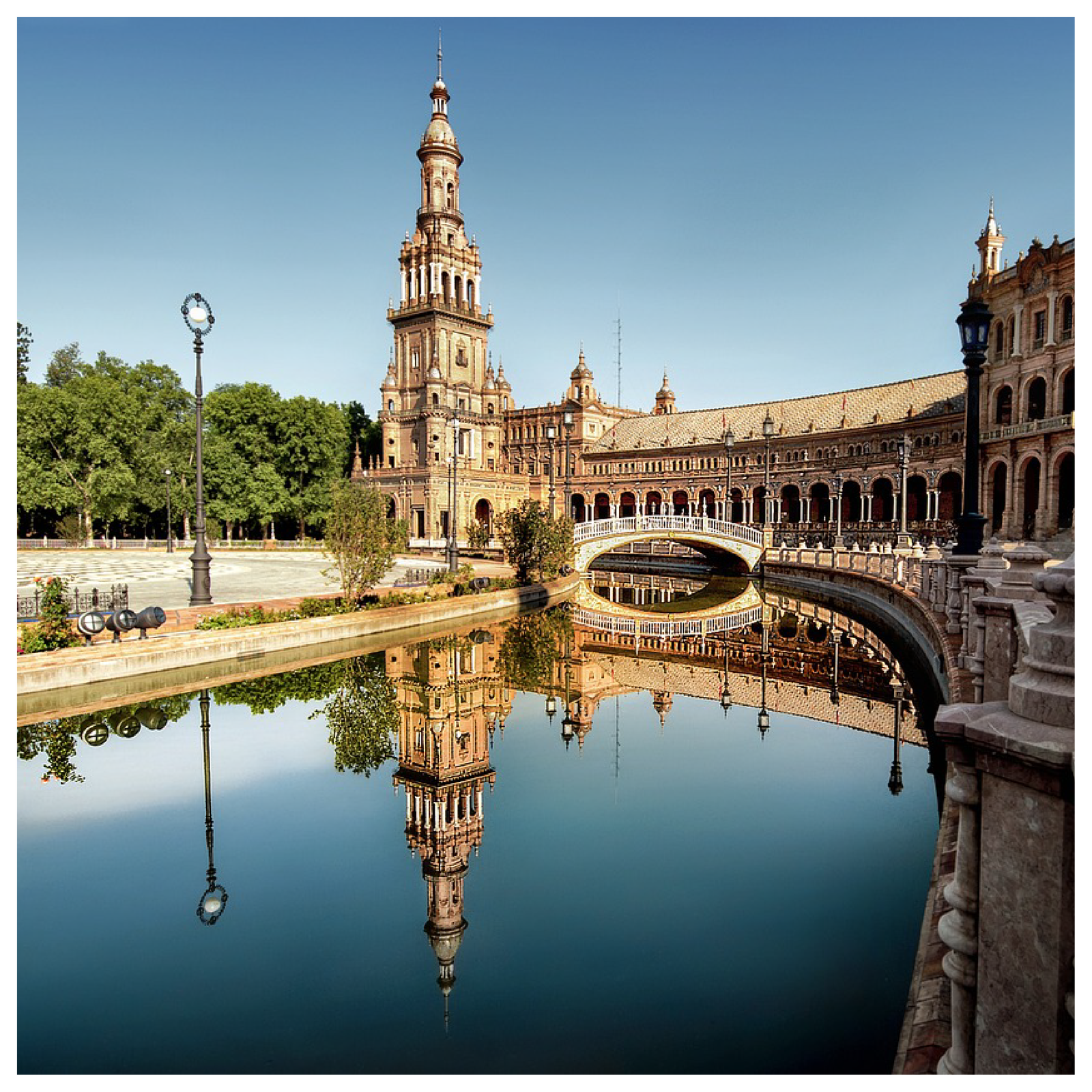 Zdjęcie przedstawiające zabytkowy budynek z kolumnami i wieżą odbijający się w wodzie.