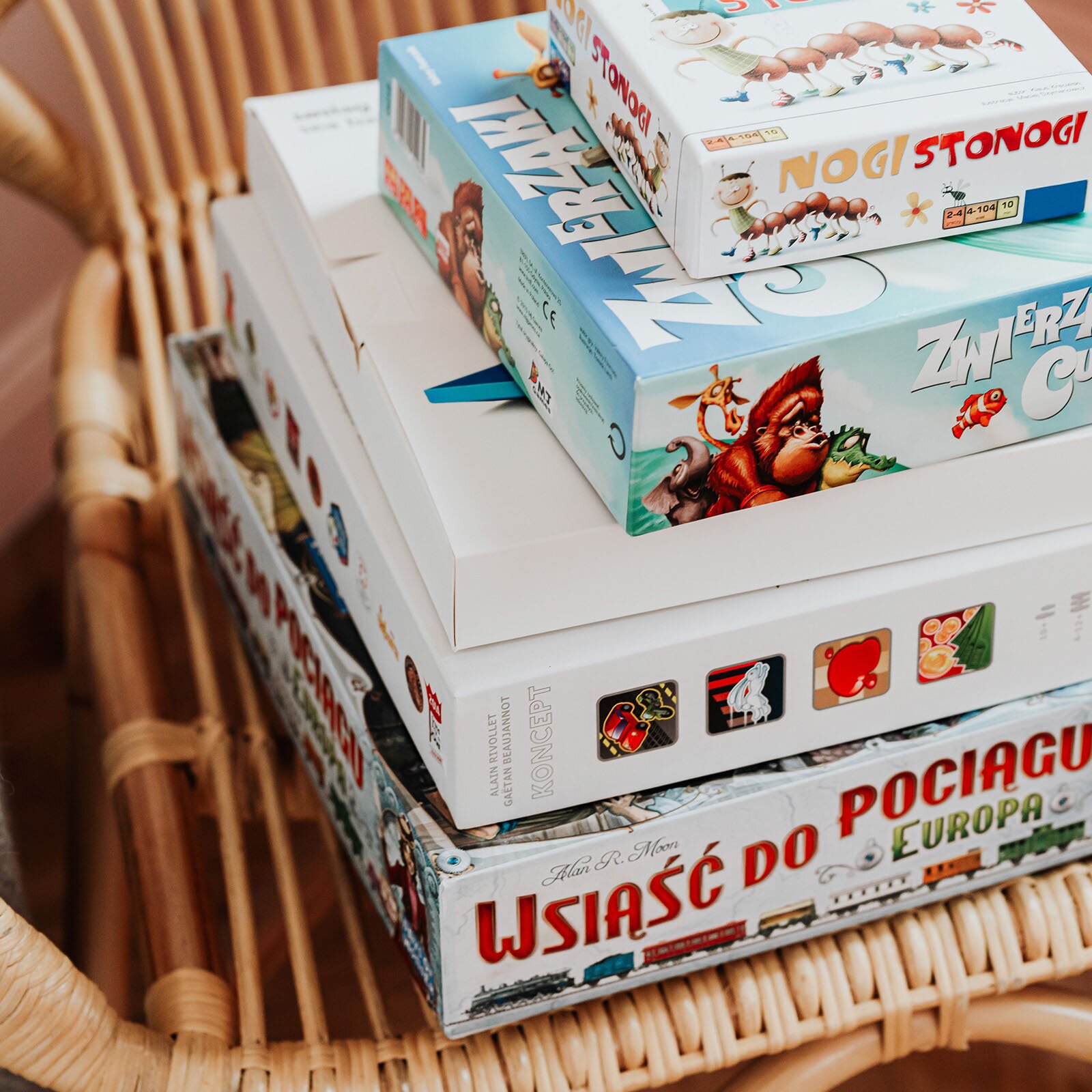 Zdjęcie przedstawia ułożone na sobie różne pudełka z grami planszowymi. 