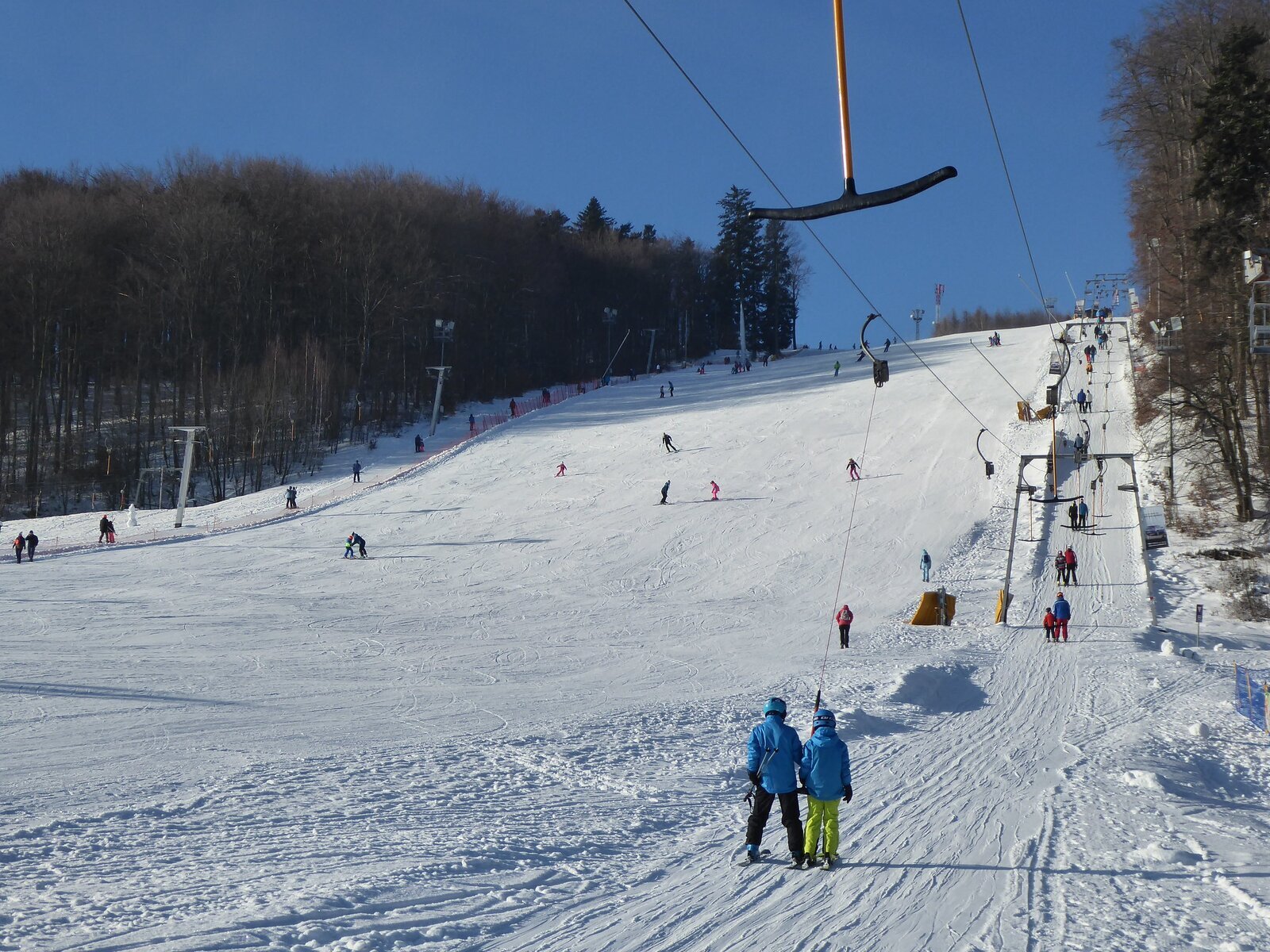 Fotografia stoku narciarskiego oraz wyciągu w trakcie sezonu zimowego.
