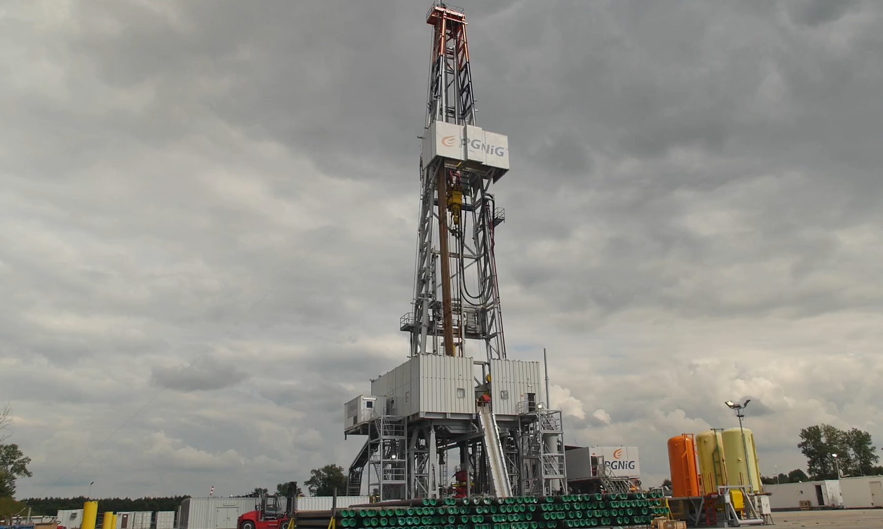 Na zdjęciu widoczny jest wieżomaszt. Wieżomaszt jest konstrukcją kratową przypominającą kształtem literę A. Widoczny na zdjęciu wieżomasz składa się z dwóch poziomów. Na dolnym pokładzie znajduje się duża szara obudowa wykonana z blachy falistej. Po prawej stronie wieżomasztu znajduje się drabina prowadząca na górny poziom. Środkiem wieżomaztu biegnie rura wydobywcza.Wieżomaszt jest na tle nieba.