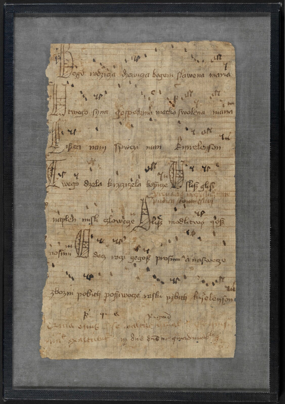 Fotografia przedstawia najstarszy zachowany rękopis „Bogurodzicy” z 1407 r. z Biblioteki Jagiellońskiej w Krakowie. Kartka jest pożółkła, z oberwanym brzegiem, oprawiona w czarną ramkę.