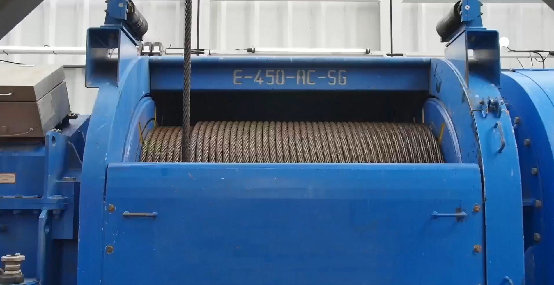 Na zdjęciu widac niebieski wyciąg wiertniczy: szpule oraz stalową linę. WYciąg wiertniczy jest to podzespół odpowiedzialny za nawijanie liny wiertniczej.