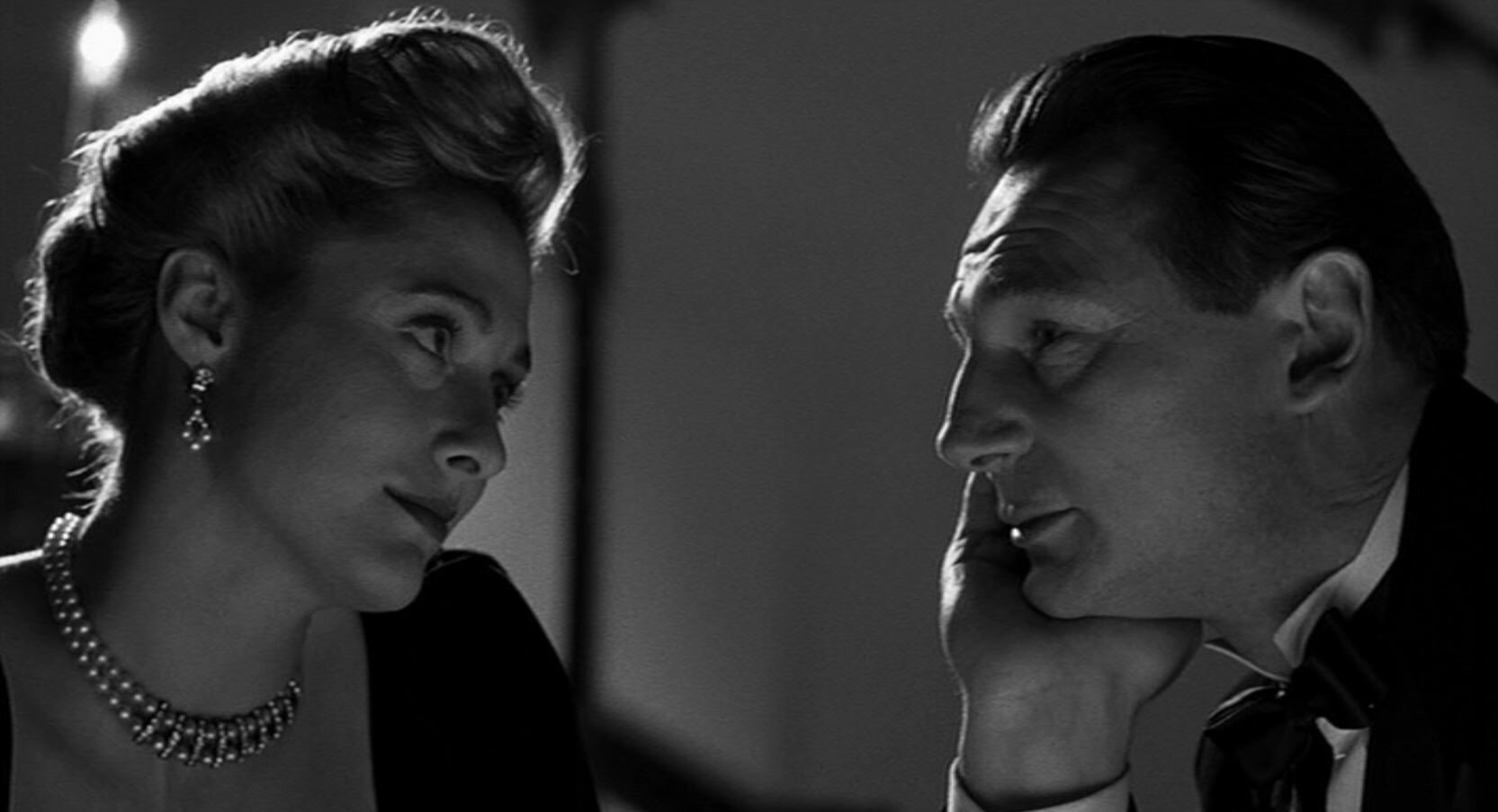 Zdjęcie przedstawia Schindlera. Na wprost niego znajduje się młoda kobieta, blondynka w kolii i kolczykach wysadzanych kamieniami. Dotyka lewą dłonią policzka mężczyzny.