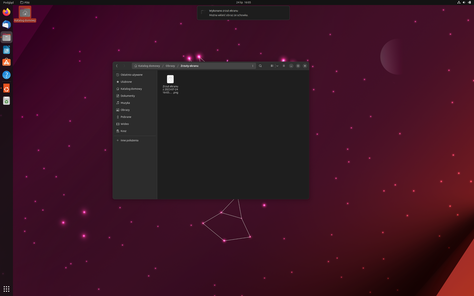 Ilustracja przedstawia pulpit Ubuntu w wersji 23.04. Na tapecie znajduje się homar złożony z figur geometrycznych. W lewym górnym rogu znajduje się ikona folderu katalogu domowego. Na środku pulpitu znajduje się okno przedstawiające zawartość folderu Obrazy.