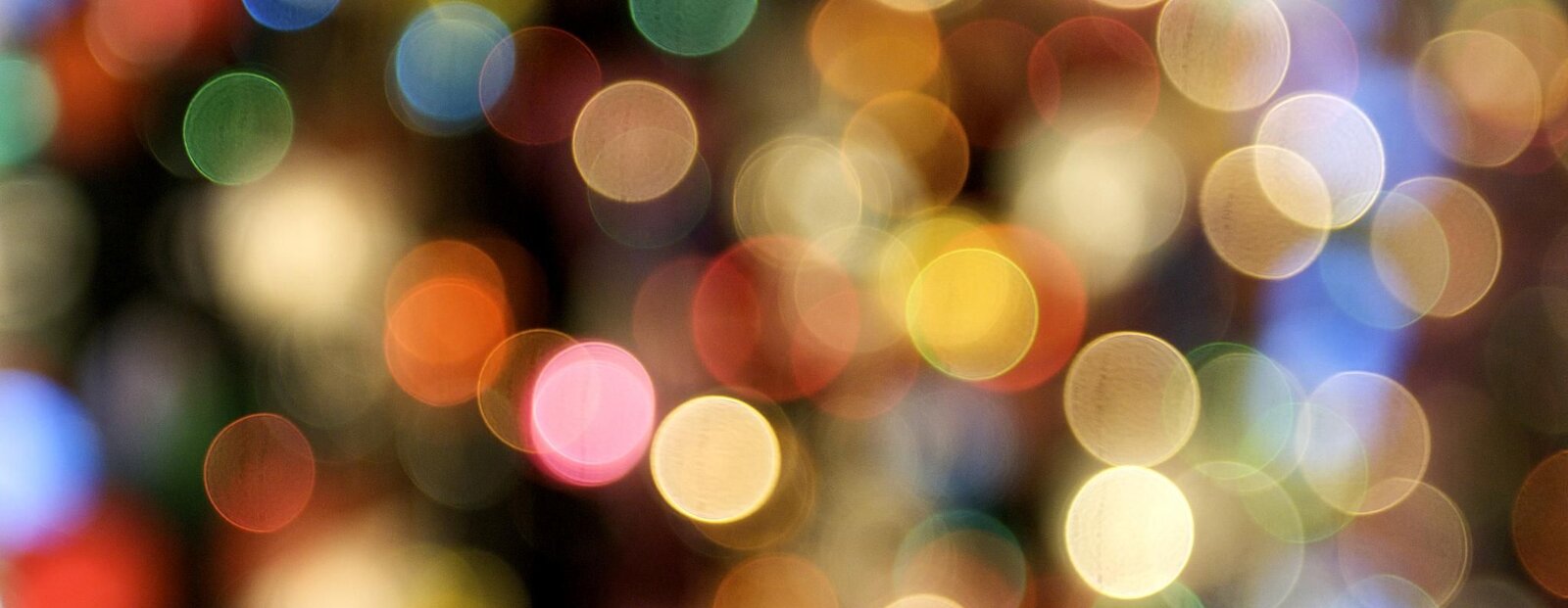 Fotografia barwna przedstawiająca wiele kolorowych, niewielkich kółeczek wypełniających całą przestrzeń kadru. Nie są rozmieszczone równomiernie, ale raczej przypadkowo, często na siebie nachodząc. W niektórych miejscach zostaje po nich tylko cień. Dalej, w tle, kilka większych kółek, które tworzą wrażenie świetlne.