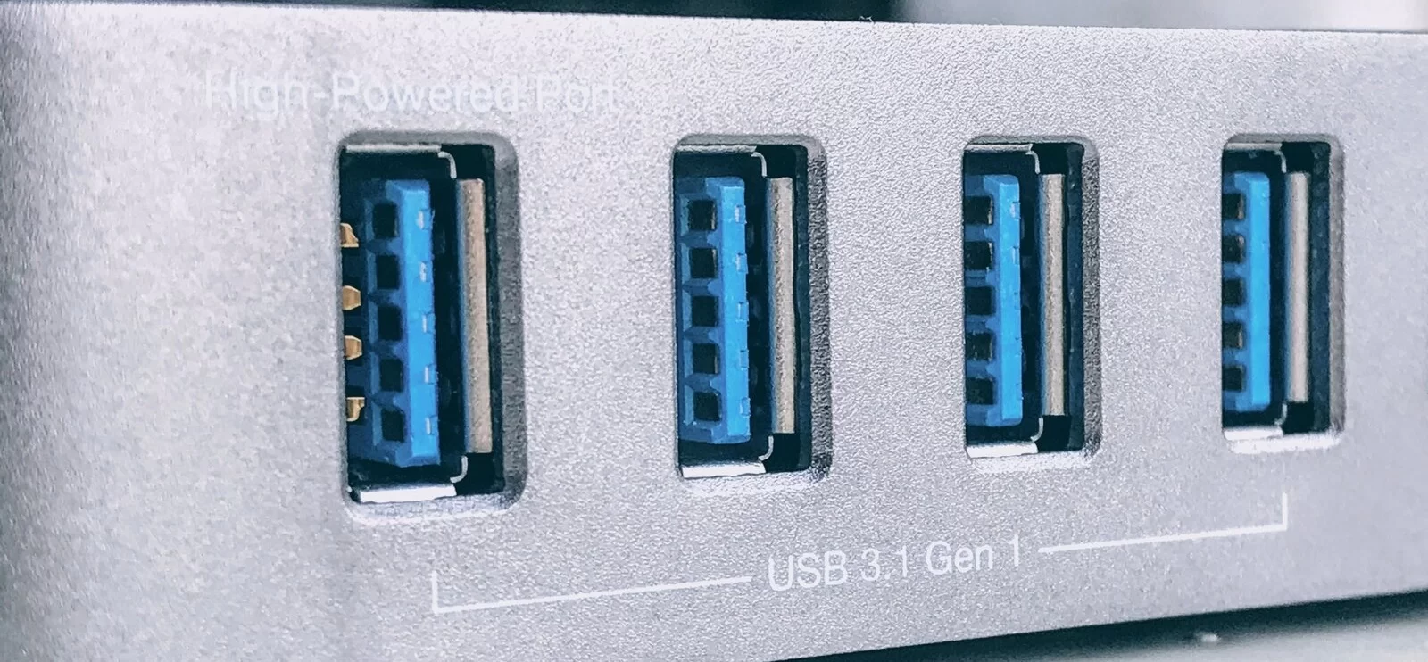 Fotografia przedstawiająca cztery gniazda USB - ustawione pionowo prostokątne niebieskie otwory z odstającą w środku płaską płytką/stykiem. Podpisane są USB 3.1 Gen 01 . 
